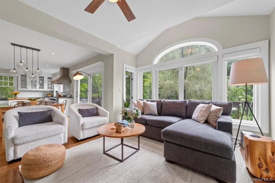 Living room with high vaulted ceiling, a wealth of natural light, light wood-type flooring, and ceiling fan Living room with high vaulted ceiling, a wealth of natural light, light wood-type flooring, and ceiling fan