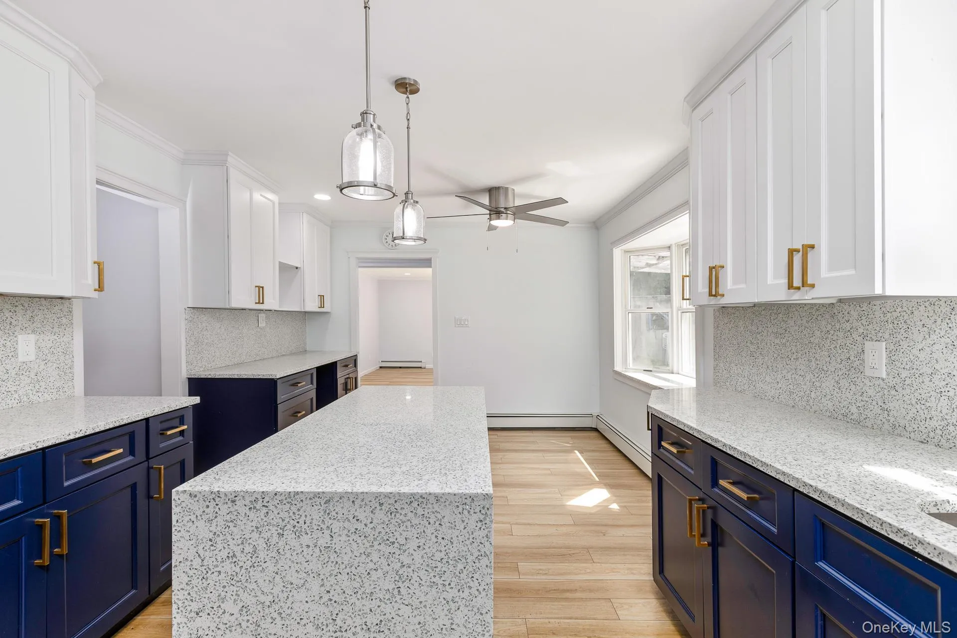 Kitchen featuring a two-tone cabinetry design, a waterfall island, pendant lighting, and a ceiling fan Kitchen featuring a two-tone cabinetry design, a waterfall island, pendant lighting, and a ceiling fan