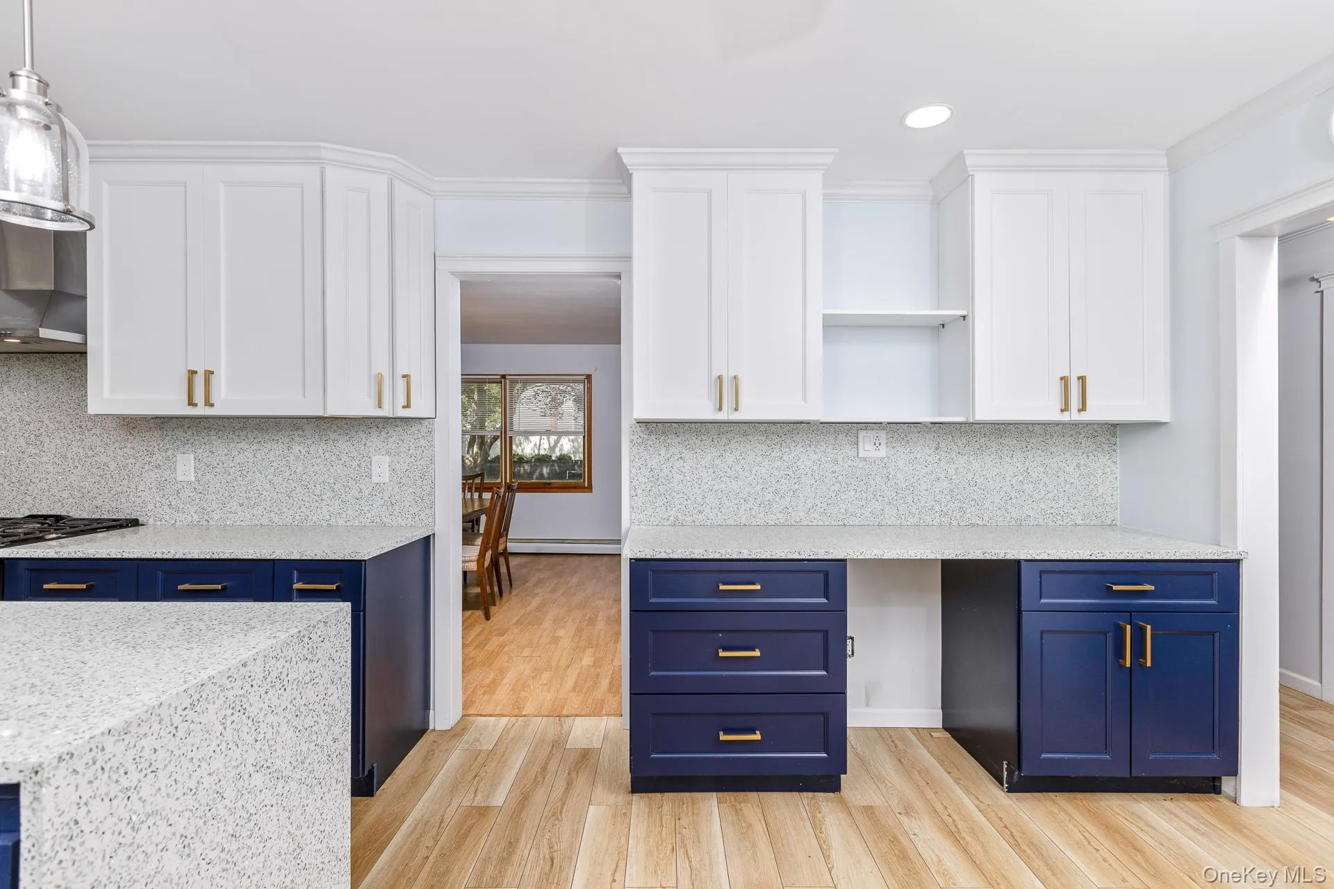Kitchen featuring two-tone cabinetry with gold-tone hardware, light-toned wood-finish flooring, recessed lighting, and stone-finish countertops Kitchen featuring two-tone cabinetry with gold-tone hardware, light-toned wood-finish flooring, recessed lighting, and stone-finish countertops