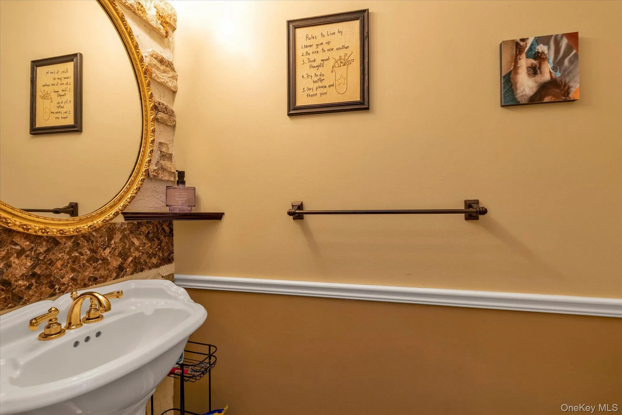 Powder room with pedestal sink featuring a gold-toned faucet with dual handles Powder room with pedestal sink featuring a gold-toned faucet with dual handles
