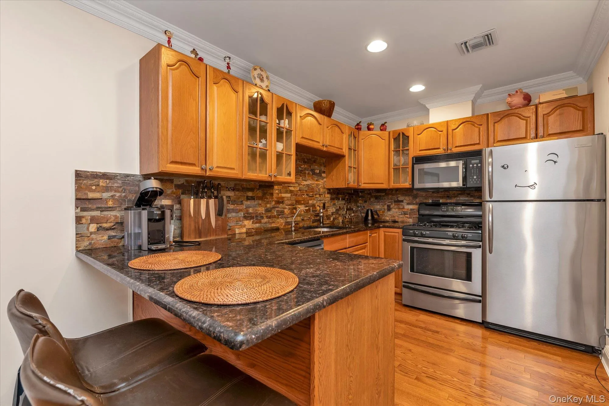 Kitchen featuring wood cabinetry, stainless steel appliances, and wood-finish flooring Kitchen featuring wood cabinetry, stainless steel appliances, and wood-finish flooring