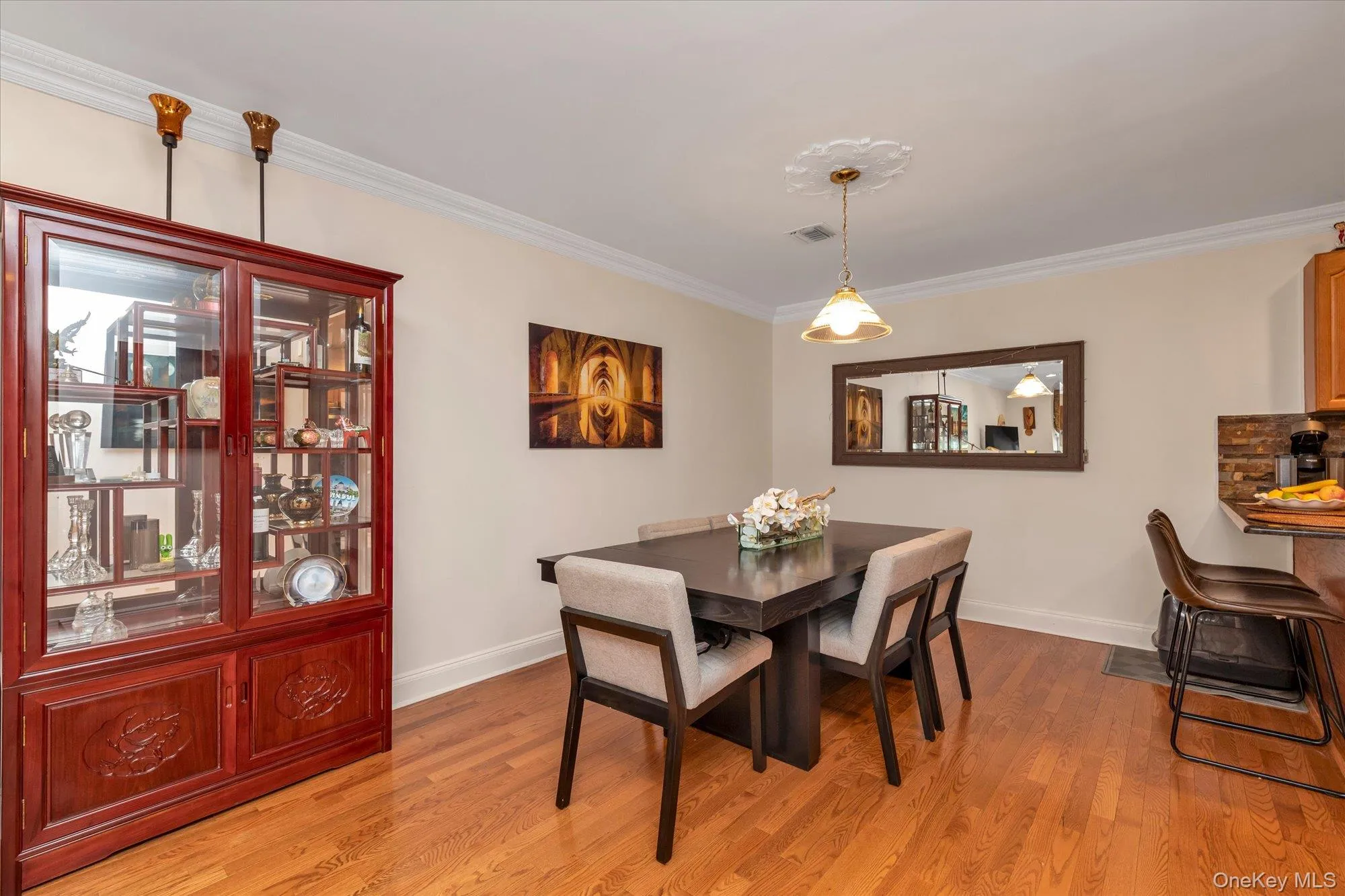 Dining room featuring wood-finish flooring, crown molding, and a decorative ceiling medallion with a pendant light fixture Dining room featuring wood-finish flooring, crown molding, and a decorative ceiling medallion with a pendant light fixture