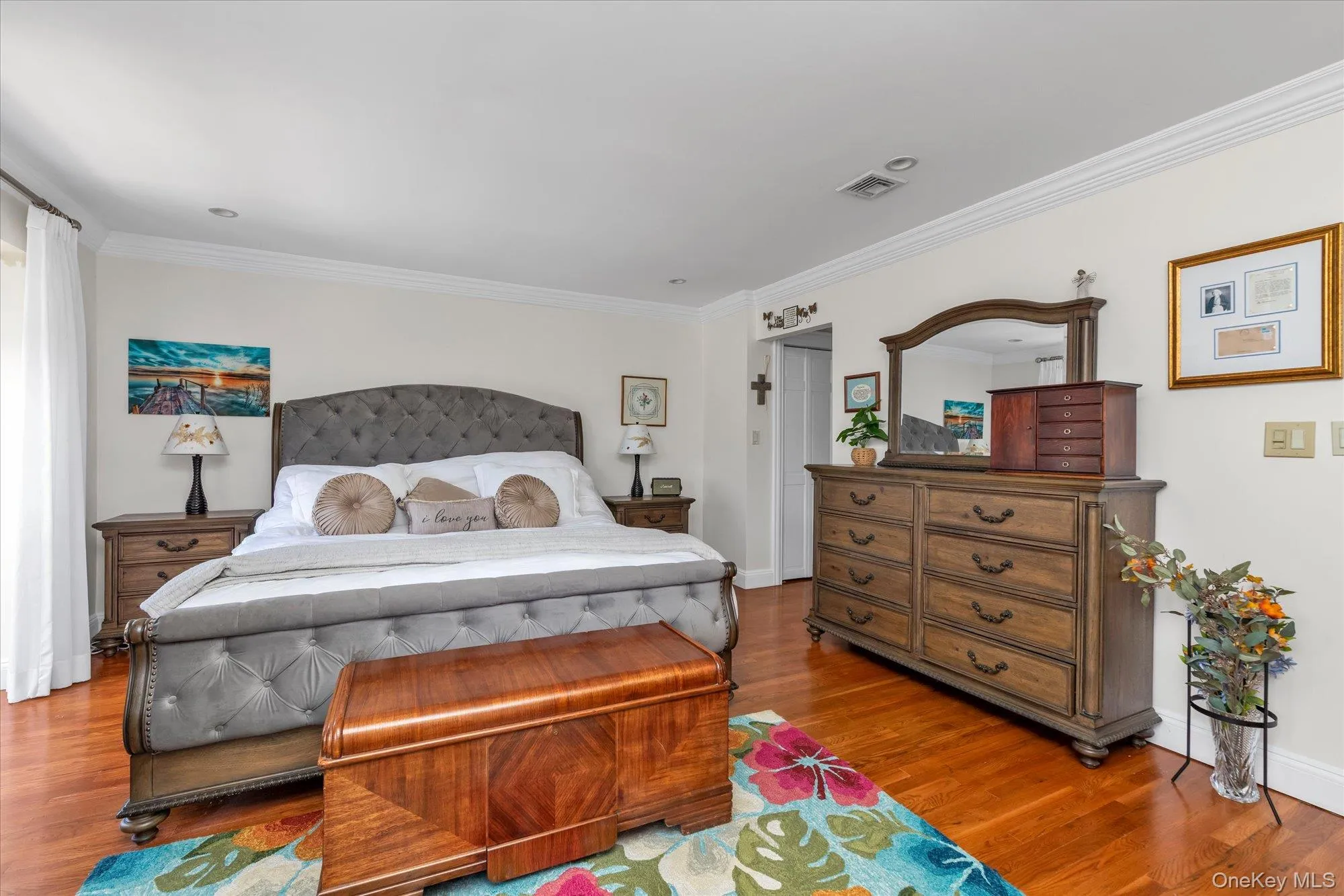 Ensuite master bedroom with 2 spacious closets, rich wood-finish flooring and crown molding and white walls Ensuite master bedroom with 2 spacious closets, rich wood-finish flooring and crown molding and white walls