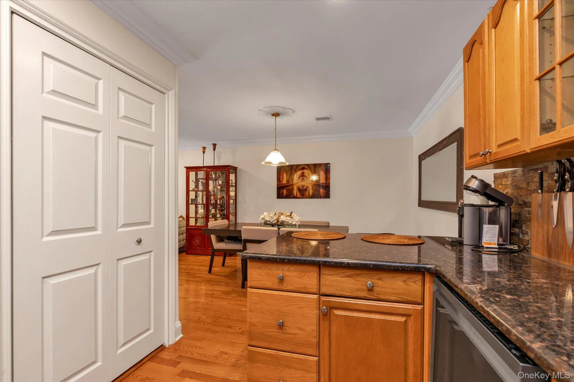 Open kitchen featuring wood-finish cabinetry, dark granite countertops, and a stone tile backsplash and washer dryer area. Open kitchen featuring wood-finish cabinetry, dark granite countertops, and a stone tile backsplash and washer dryer area.