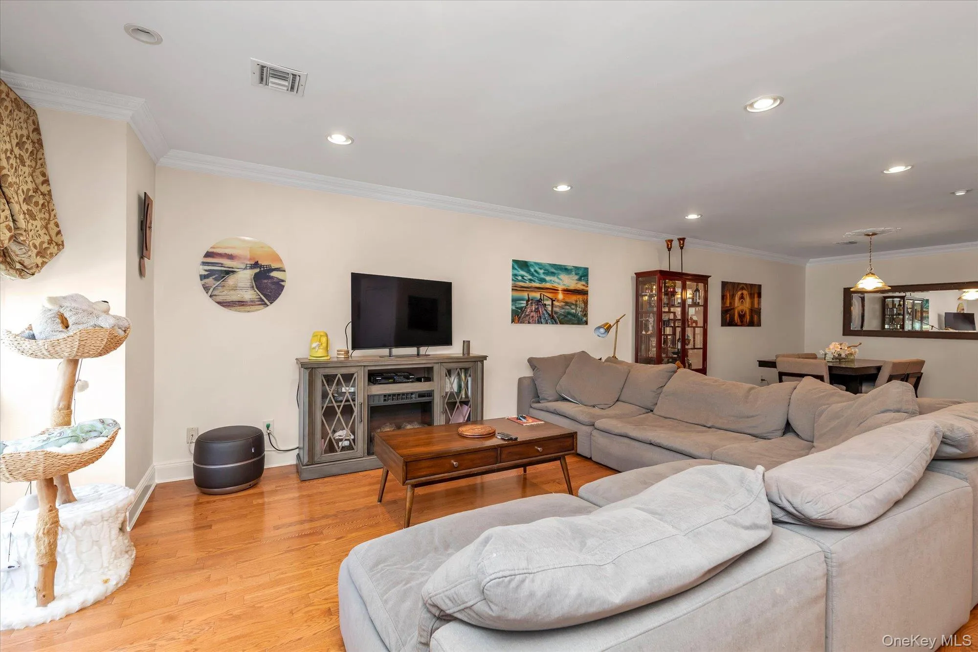Open-concept living room featuring hardwood flooring, recessed lighting, and crown molding Open-concept living room featuring hardwood flooring, recessed lighting, and crown molding