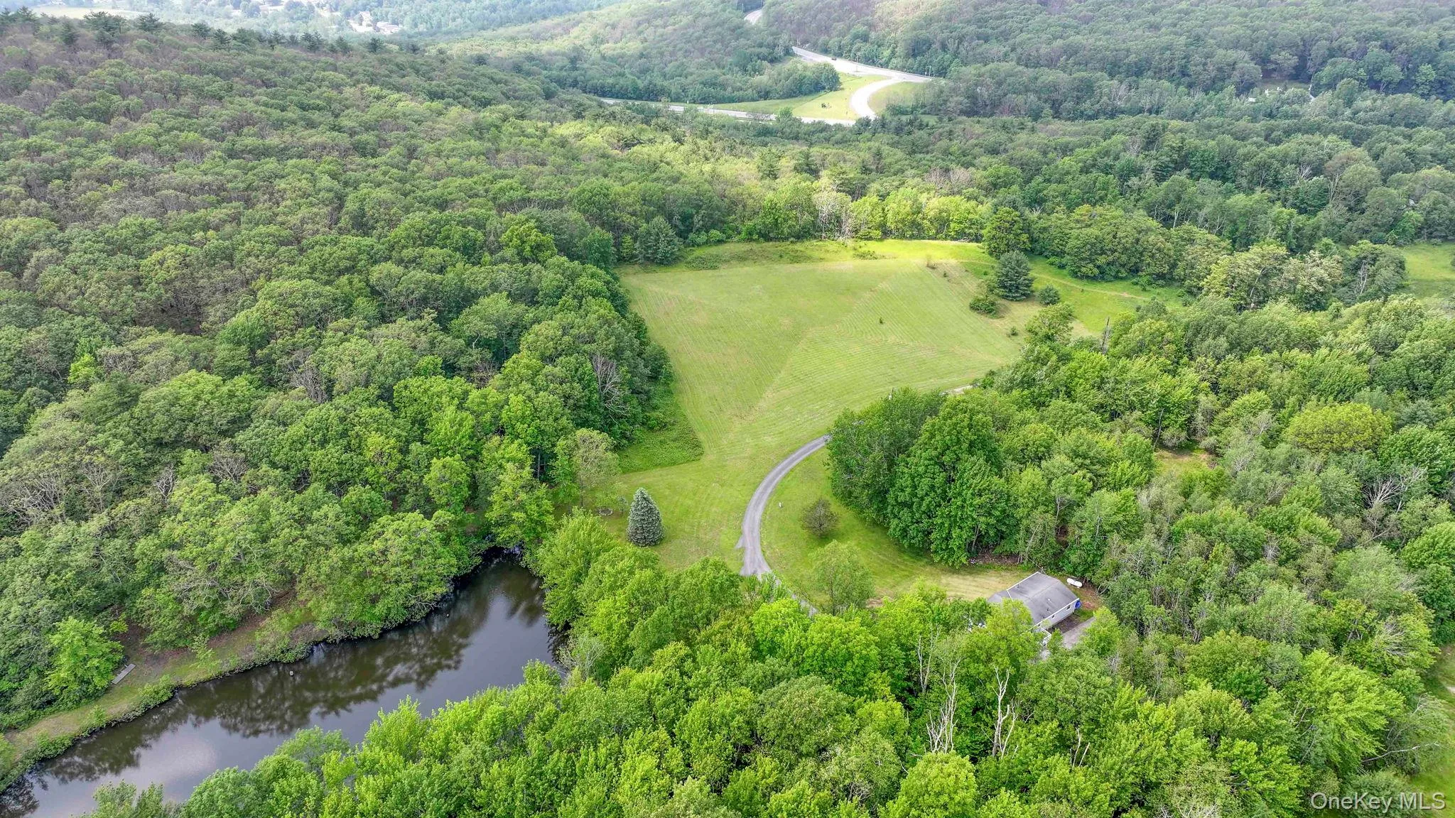 Aerial overview of property's location with a heavily wooded area and a nearby body of water Aerial overview of property's location with a heavily wooded area and a nearby body of water