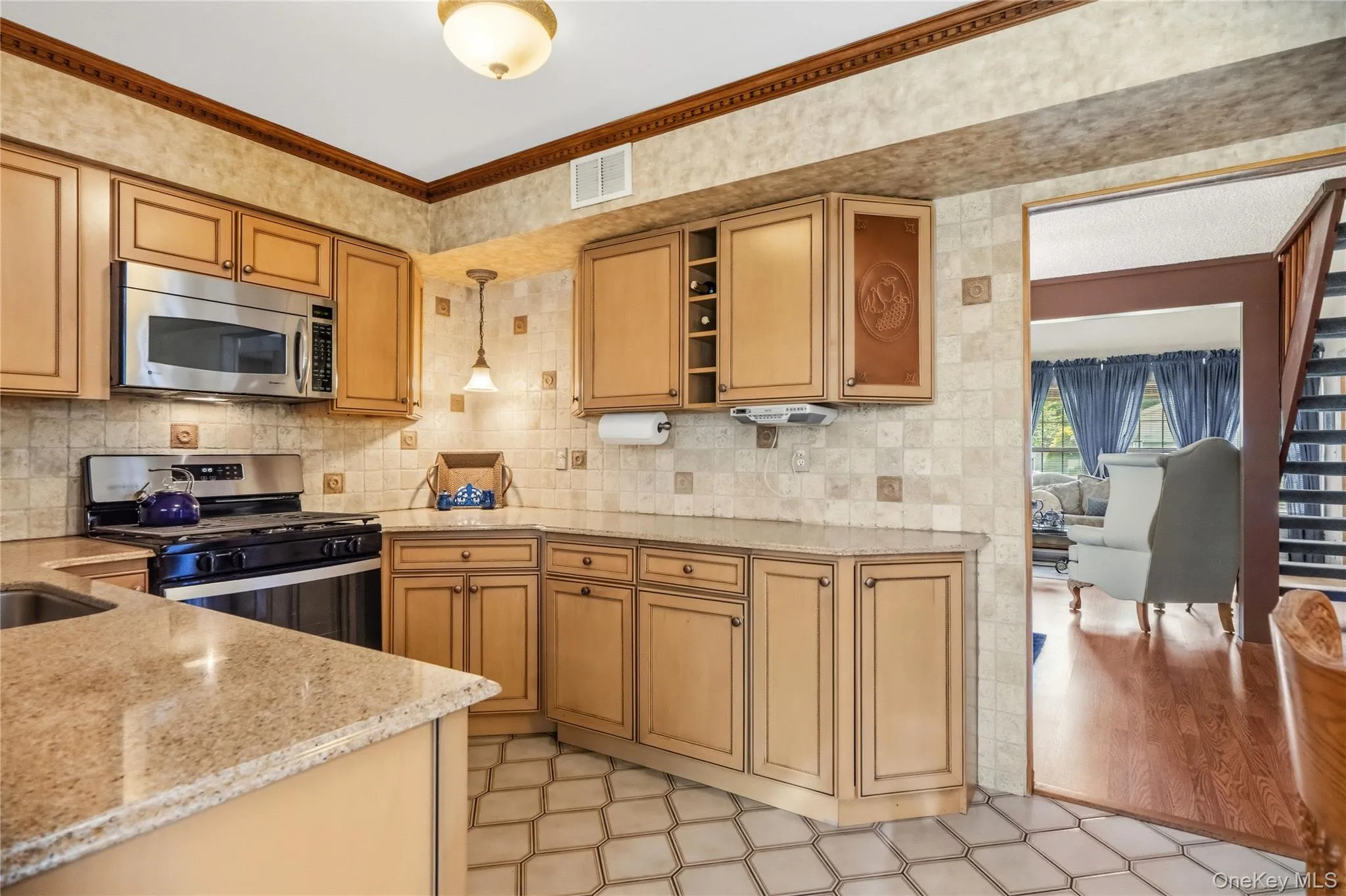 The kitchen features light toned wood cabinets, granite counter tops, a tiled backsplash, built in wine storage and is accented by the darker toned crown molding. The kitchen features light toned wood cabinets, granite counter tops, a tiled backsplash, built in wine storage and is accented by the darker toned crown molding.