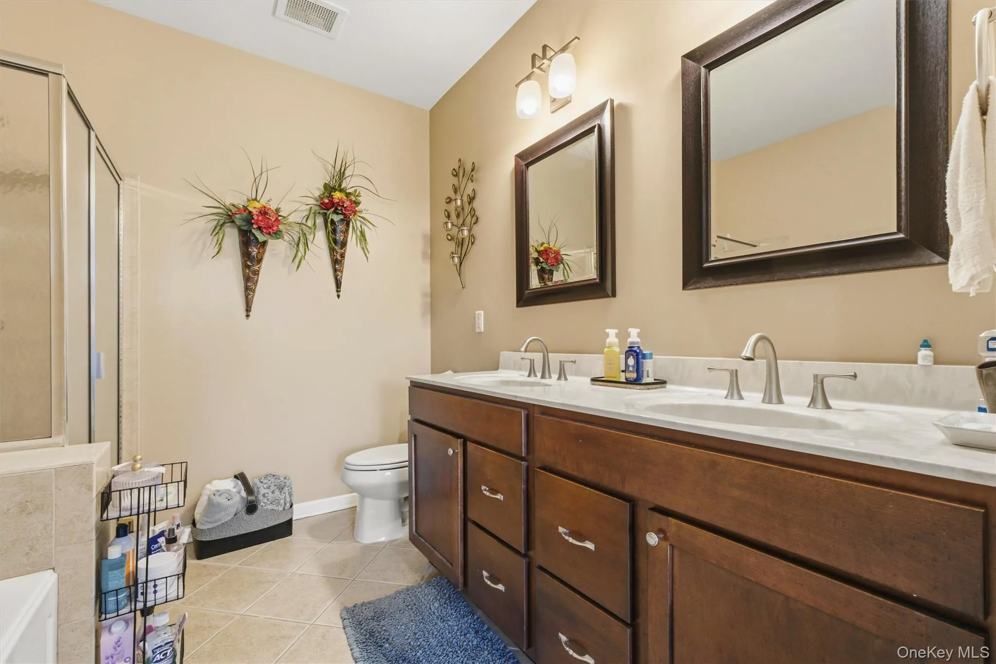 The en suite bath is thoughtfully appointed with dual sinks, an expansive custom vanity, a deep whirlpool soaking tub, and a separate glass-enclosed shower—creating a spa-like setting ideal for unwinding at the end of the day. The en suite bath is thoughtfully appointed with dual sinks, an expansive custom vanity, a deep whirlpool soaking tub, and a separate glass-enclosed shower—creating a spa-like setting ideal for unwinding at the end of the day.