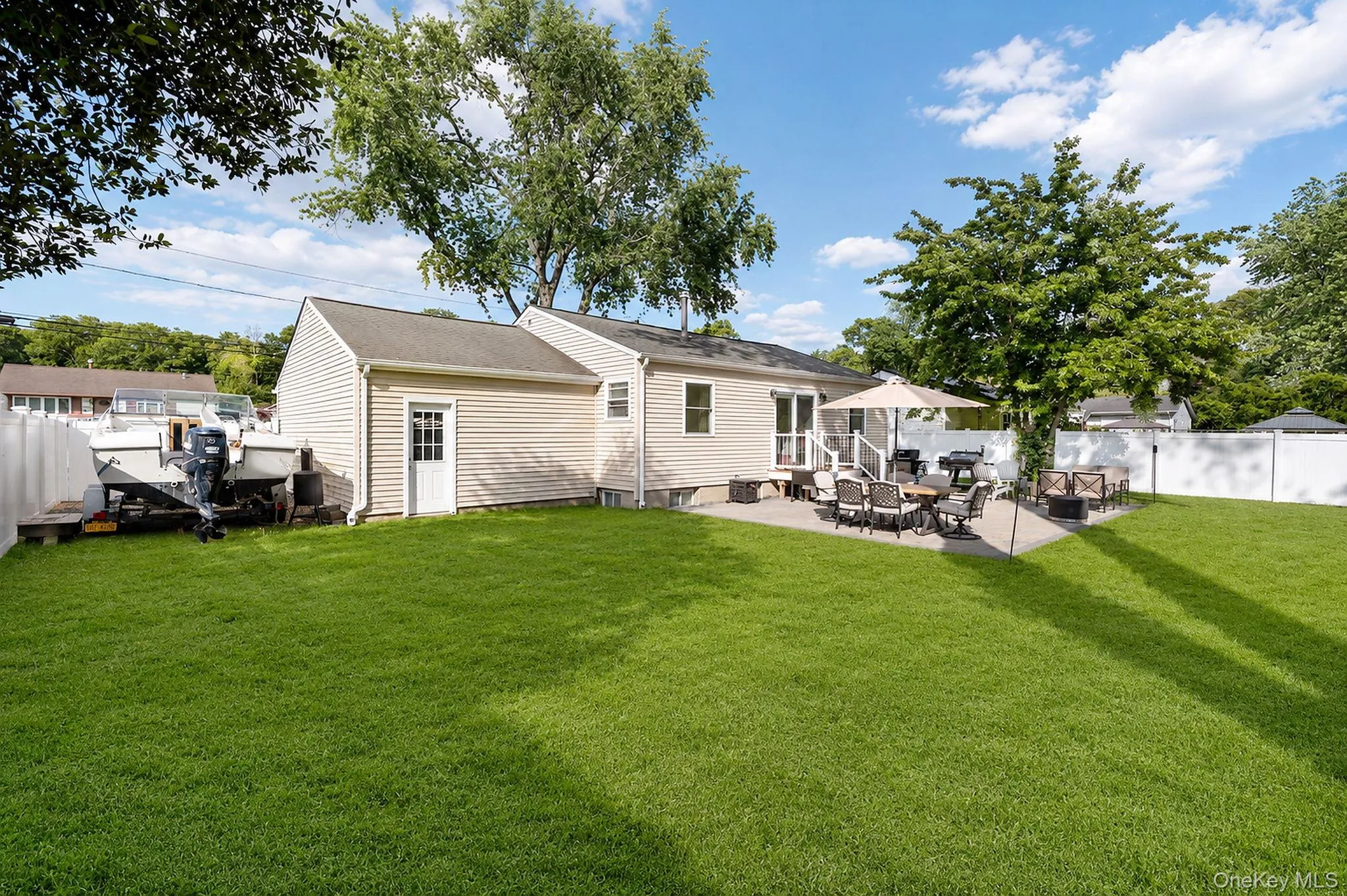 Spacious backyard featuring a large green lawn, paver patio, and white privacy fencing Spacious backyard featuring a large green lawn, paver patio, and white privacy fencing