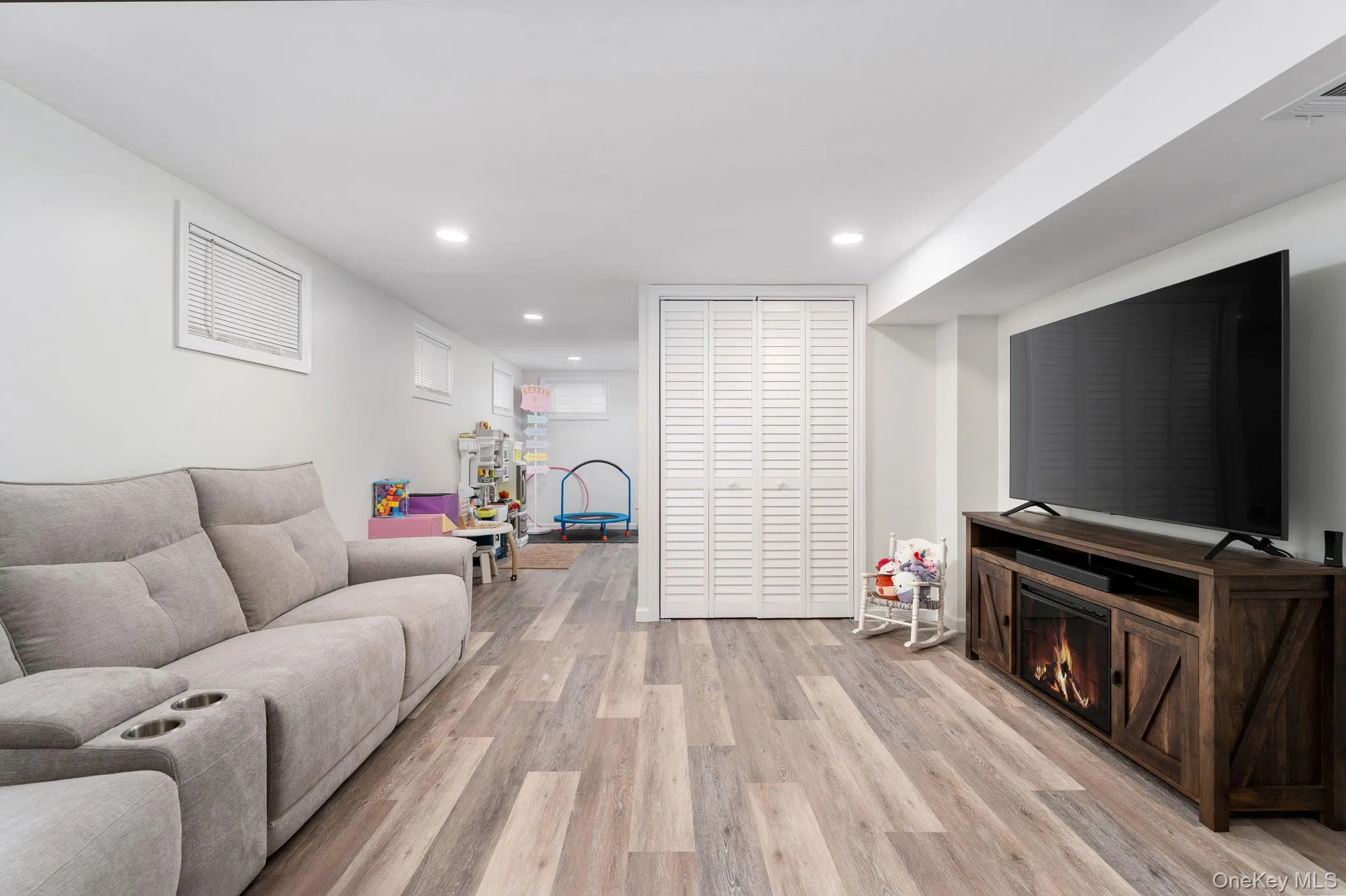 Finished lower level featuring recessed lighting, wood-finish flooring (LVP), and a console with an electric fireplace Finished lower level featuring recessed lighting, wood-finish flooring (LVP), and a console with an electric fireplace