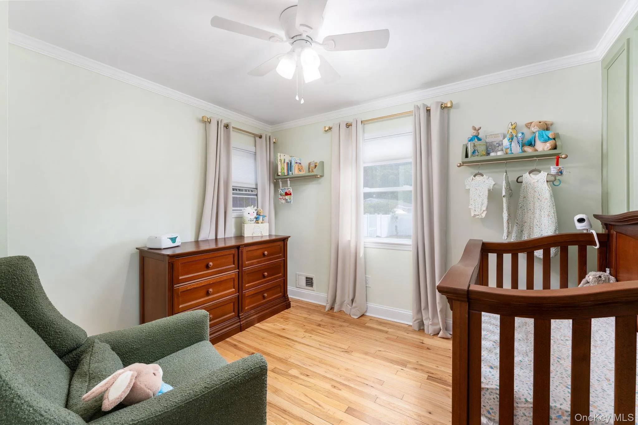Hardwood flooring throughout this room, featuring a ceiling fan, crown molding, and two windows with natural light Hardwood flooring throughout this room, featuring a ceiling fan, crown molding, and two windows with natural light