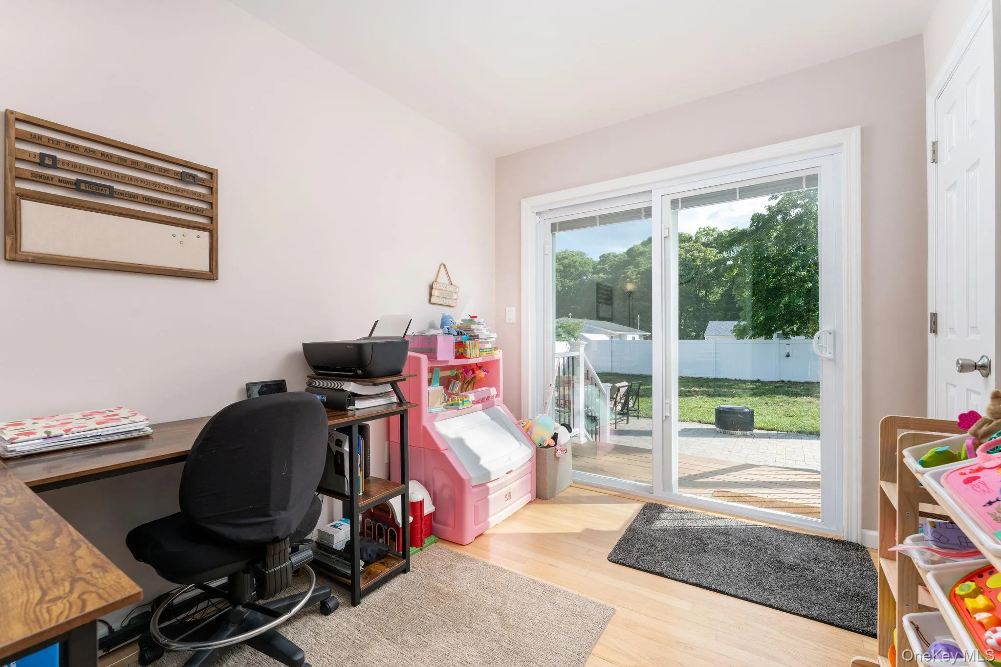 Bedroom with sliding glass patio doors going outside. Hardwood flooring throughout and light-colored walls Bedroom with sliding glass patio doors going outside. Hardwood flooring throughout and light-colored walls