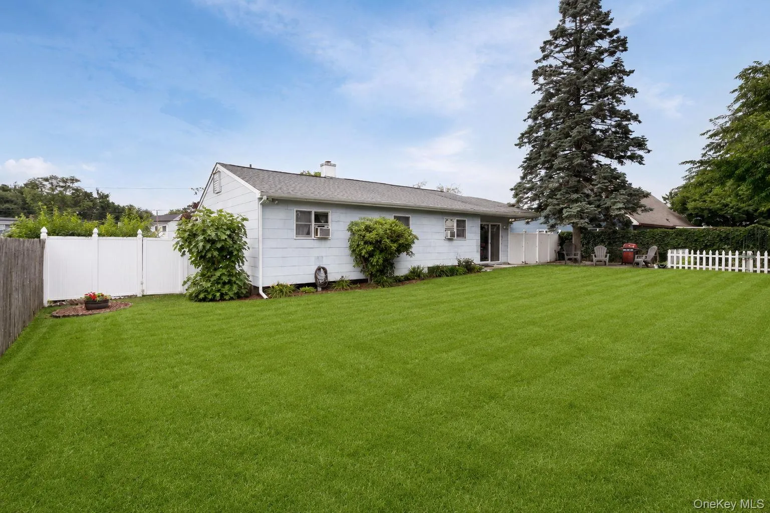 Expansive lawn area featuring a picket fence section and mature landscaping Expansive lawn area featuring a picket fence section and mature landscaping
