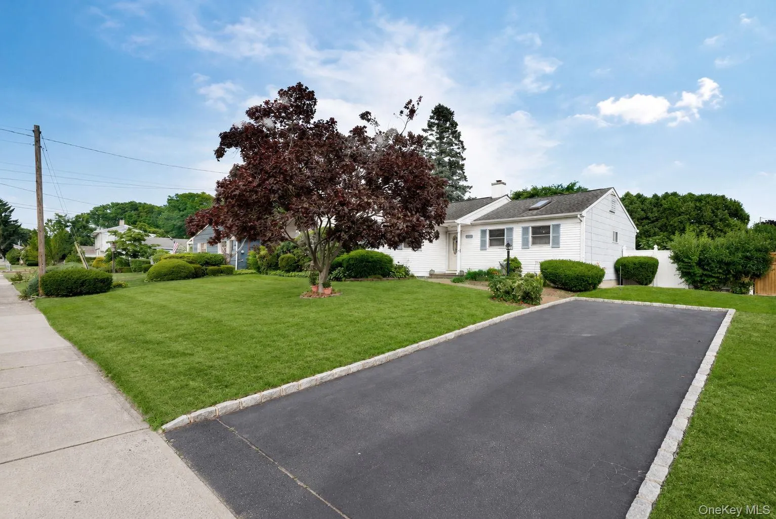 White siding residence featuring a paved driveway with Belgian block curbing White siding residence featuring a paved driveway with Belgian block curbing
