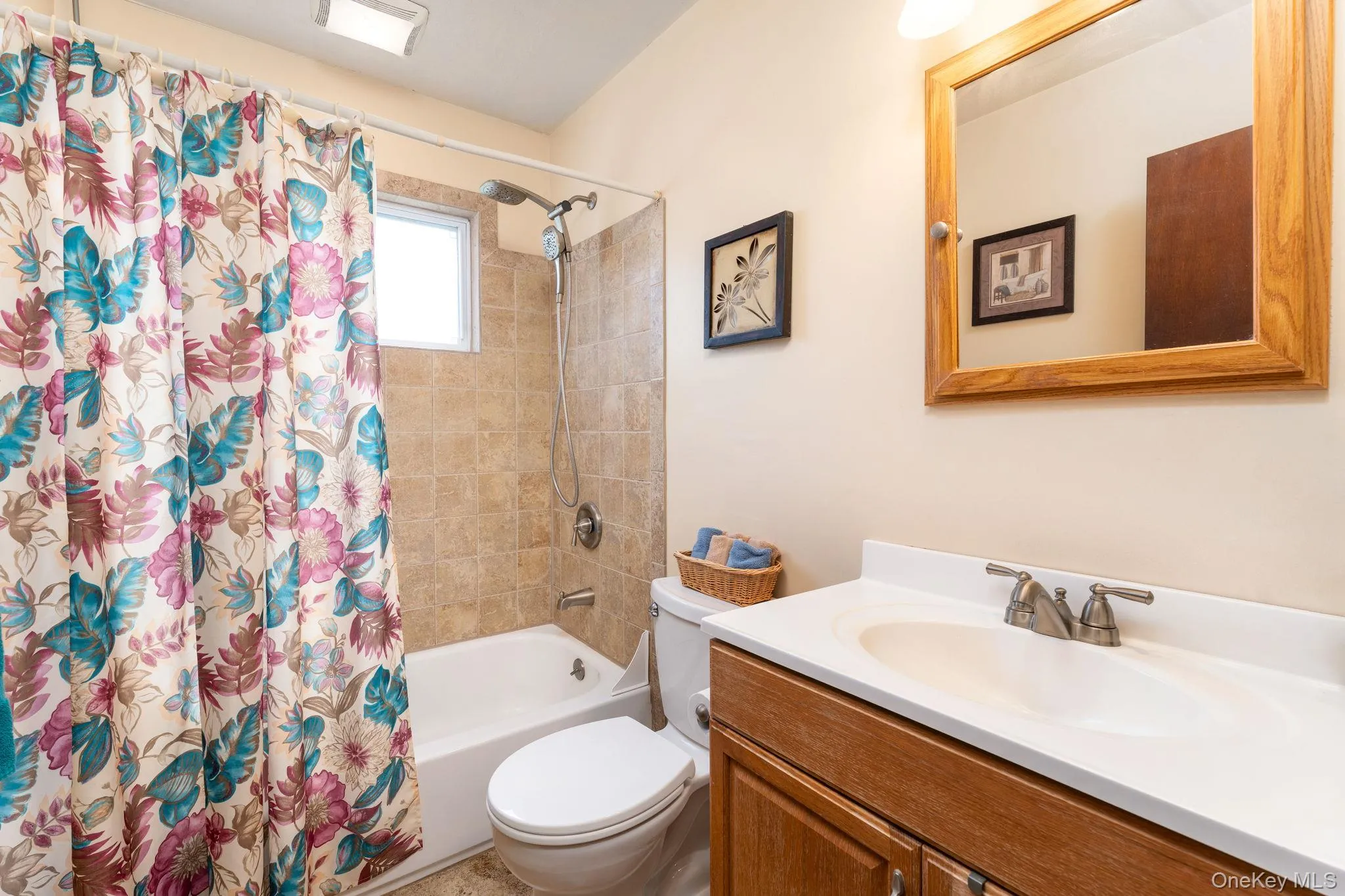 Bathroom featuring a single vanity with wood-finish cabinetry, a white integrated sink, and a framed mirror Bathroom featuring a single vanity with wood-finish cabinetry, a white integrated sink, and a framed mirror