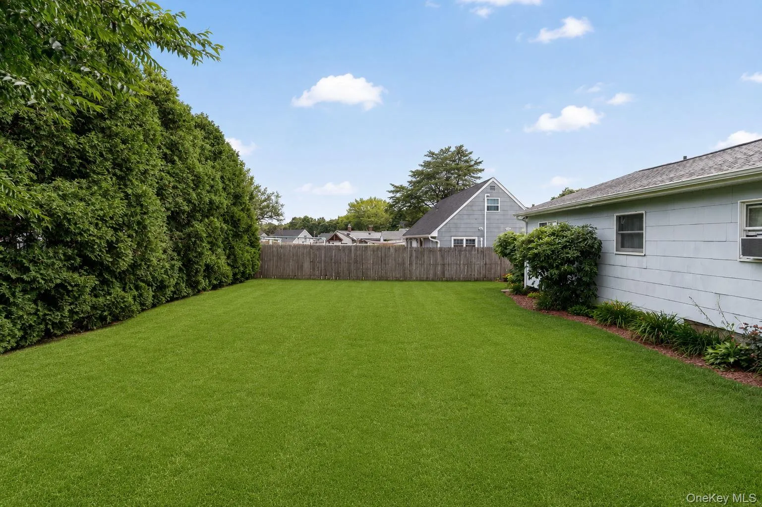Spacious, level lawn area featuring mature perimeter plantings and a rear privacy fence Spacious, level lawn area featuring mature perimeter plantings and a rear privacy fence