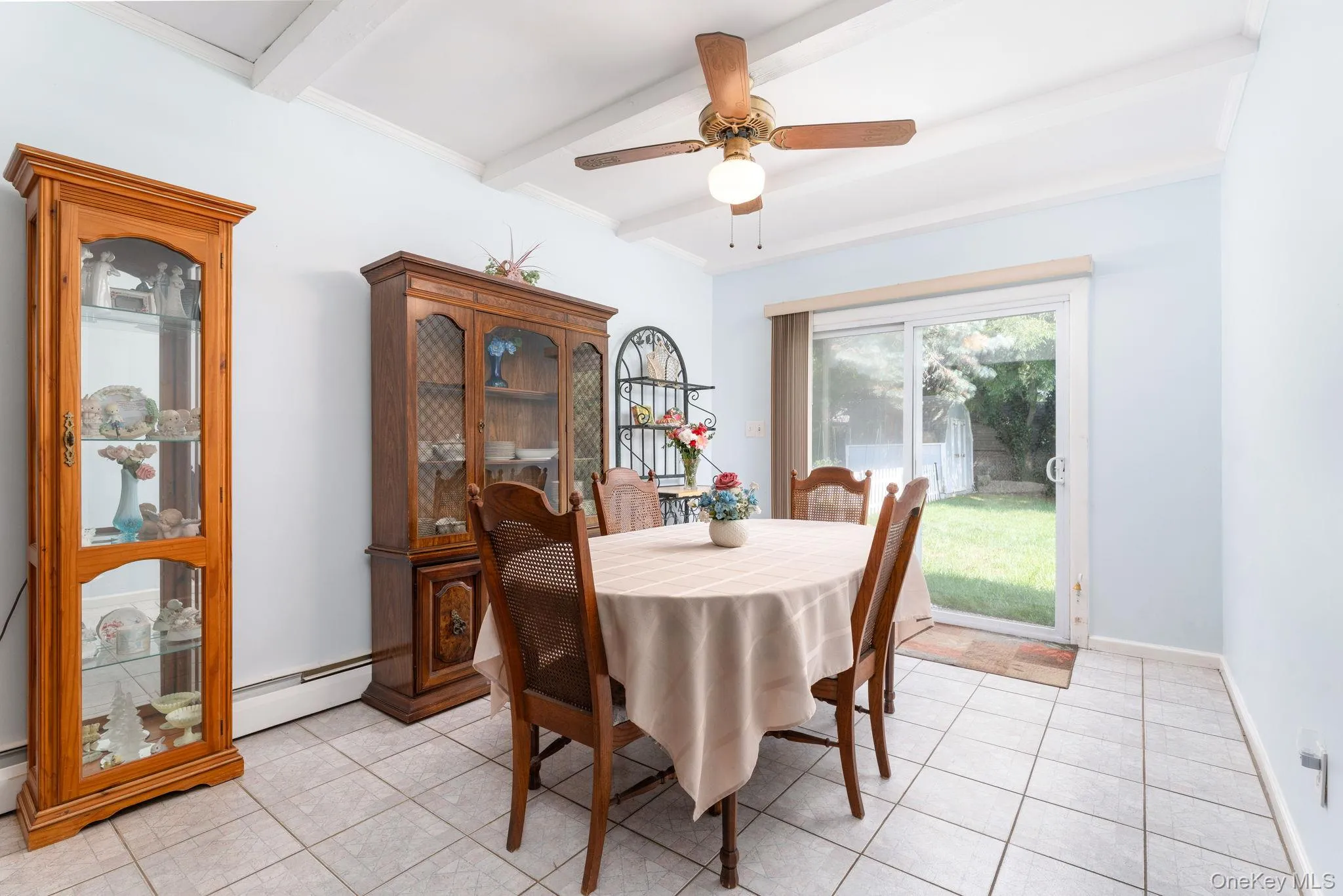 Dining area featuring white tiled flooring, a ceiling fan with integrated lighting, and exposed white ceiling beams Dining area featuring white tiled flooring, a ceiling fan with integrated lighting, and exposed white ceiling beams