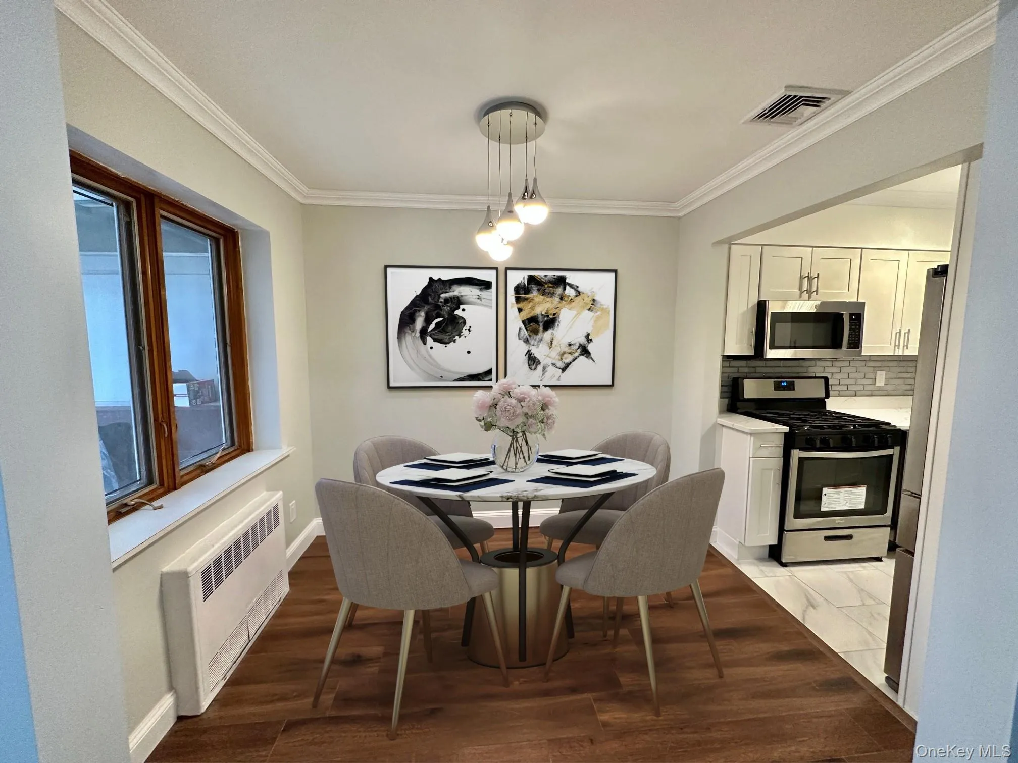 Dining area featuring warm wood-finish flooring, crown molding, and a contemporary multi-light pendant fixture Dining area featuring warm wood-finish flooring, crown molding, and a contemporary multi-light pendant fixture