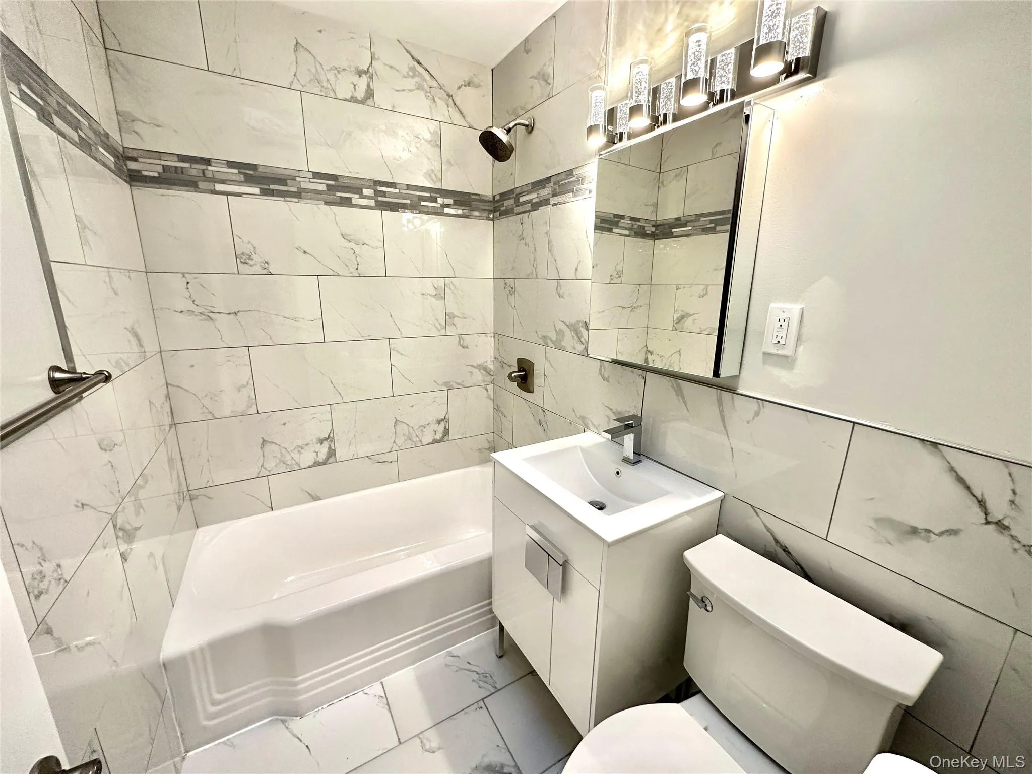 Bathroom featuring a shower/tub combination with white tile surround and decorative mosaic accent Bathroom featuring a shower/tub combination with white tile surround and decorative mosaic accent