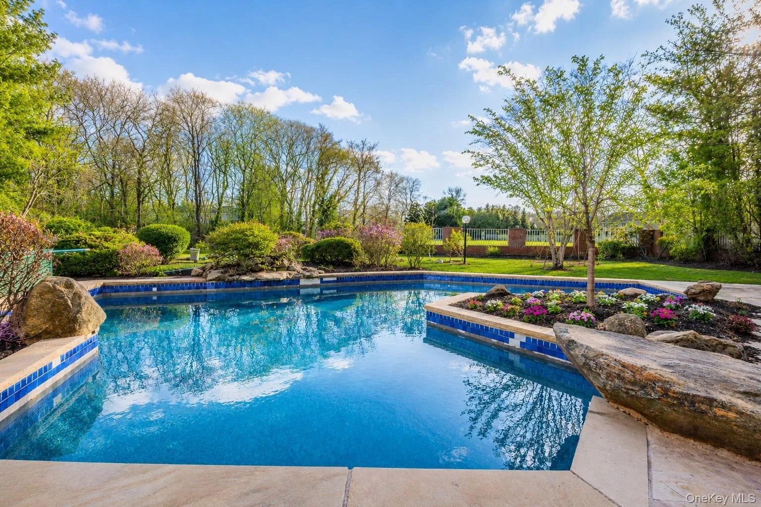 Swimming pool with blue mosaic tile accents, surrounded by a stone coping Swimming pool with blue mosaic tile accents, surrounded by a stone coping