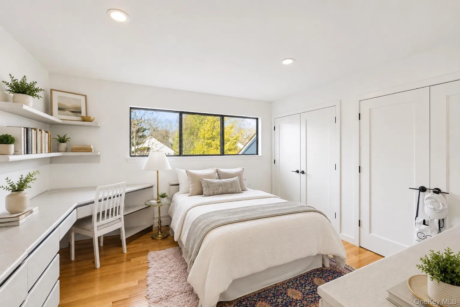 Bright room featuring wood-finish flooring, recessed lighting, a multi-pane window, built-in shelving, and two white panel doors Bright room featuring wood-finish flooring, recessed lighting, a multi-pane window, built-in shelving, and two white panel doors