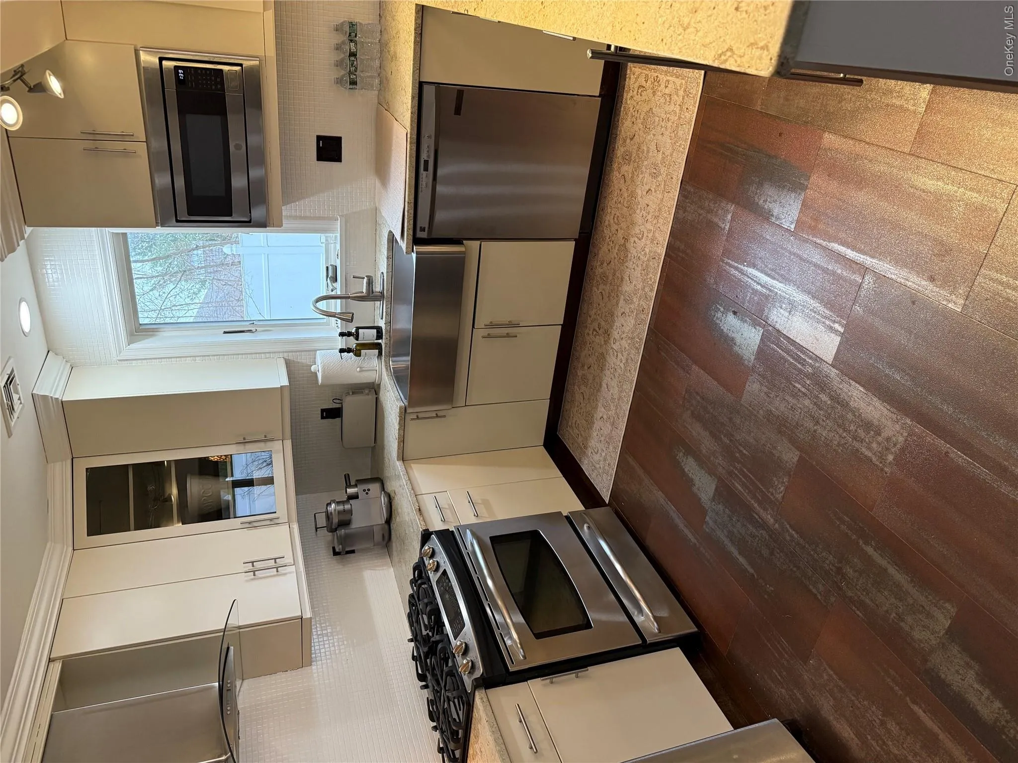 Kitchen with a sink, ventilation hood, dishwashing machine, range, and dark wood-style flooring Kitchen with a sink, ventilation hood, dishwashing machine, range, and dark wood-style flooring
