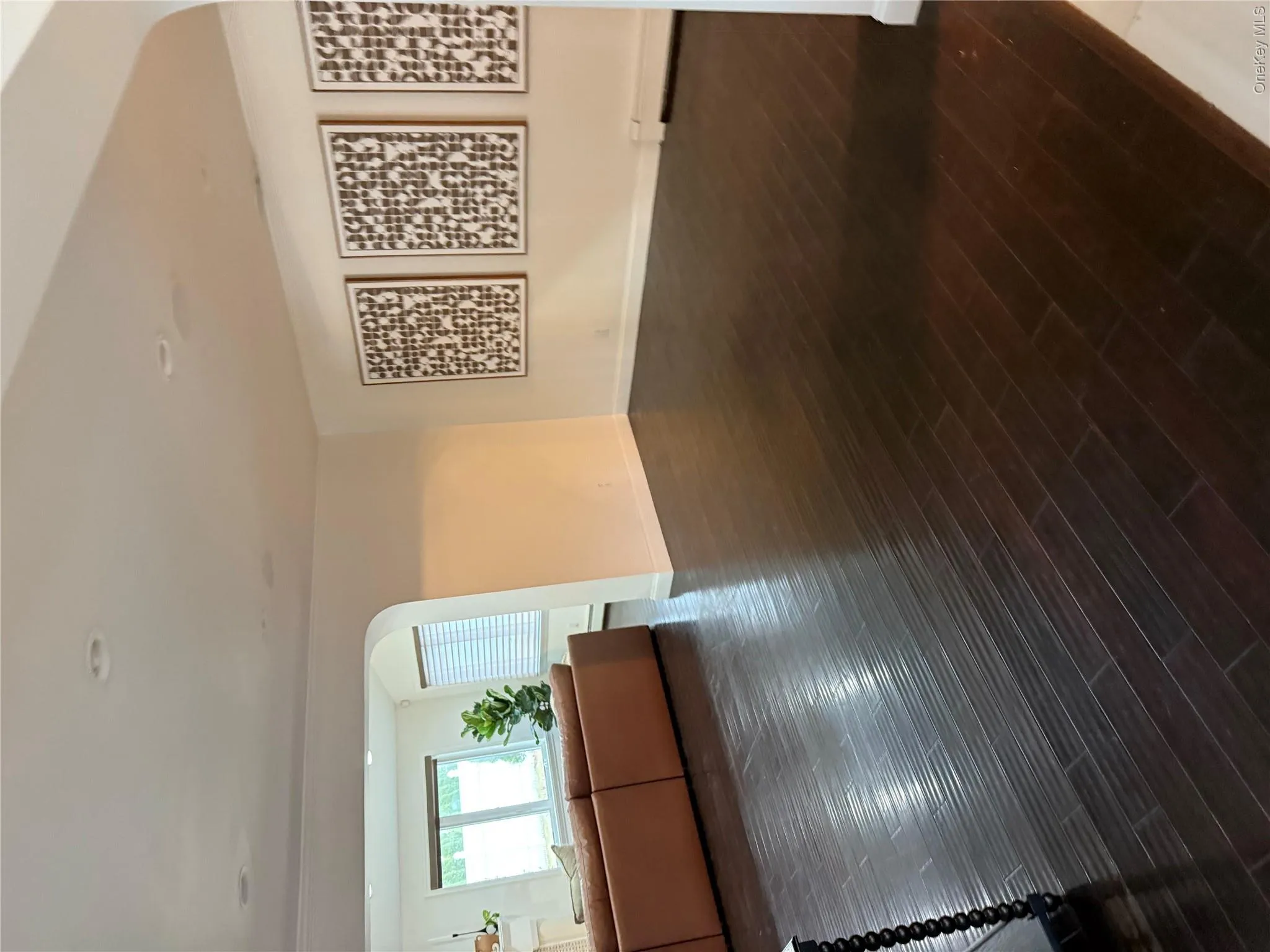 Unfurnished living room featuring a baseboard heating unit, arched walkways, baseboards, and wood finished floors Unfurnished living room featuring a baseboard heating unit, arched walkways, baseboards, and wood finished floors