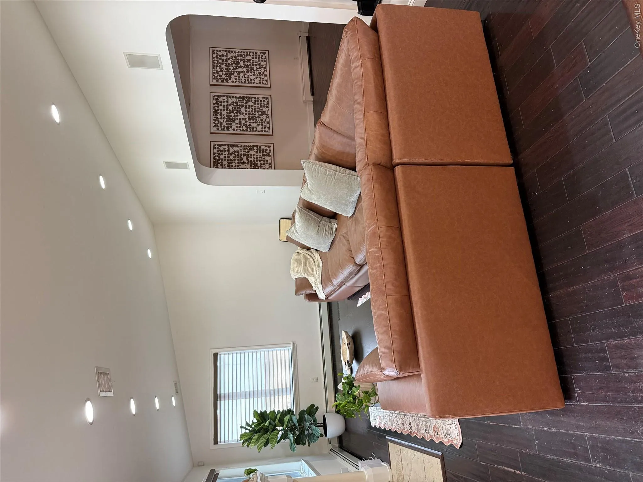 Living area featuring arched walkways, visible vents, dark wood-type flooring, and vaulted ceiling Living area featuring arched walkways, visible vents, dark wood-type flooring, and vaulted ceiling