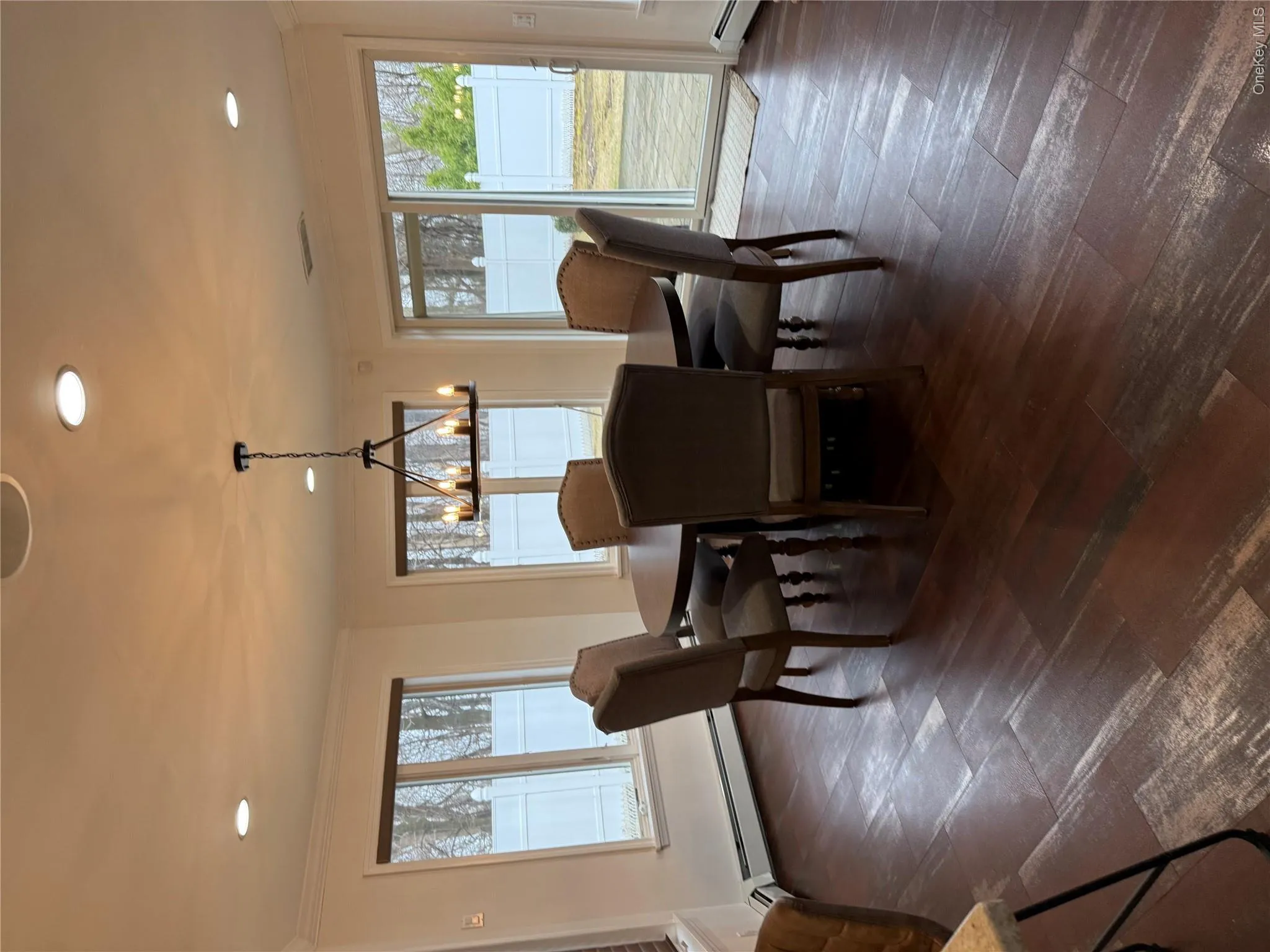 Dining space featuring a notable chandelier, dark wood-style floors, baseboard heating, and ornamental molding Dining space featuring a notable chandelier, dark wood-style floors, baseboard heating, and ornamental molding