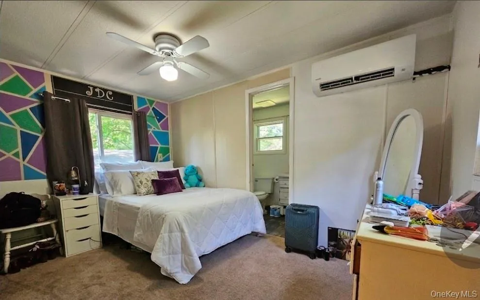 Carpeted bedroom featuring a ceiling fan with integrated lighting, a window, and an air conditioning unit Carpeted bedroom featuring a ceiling fan with integrated lighting, a window, and an air conditioning unit