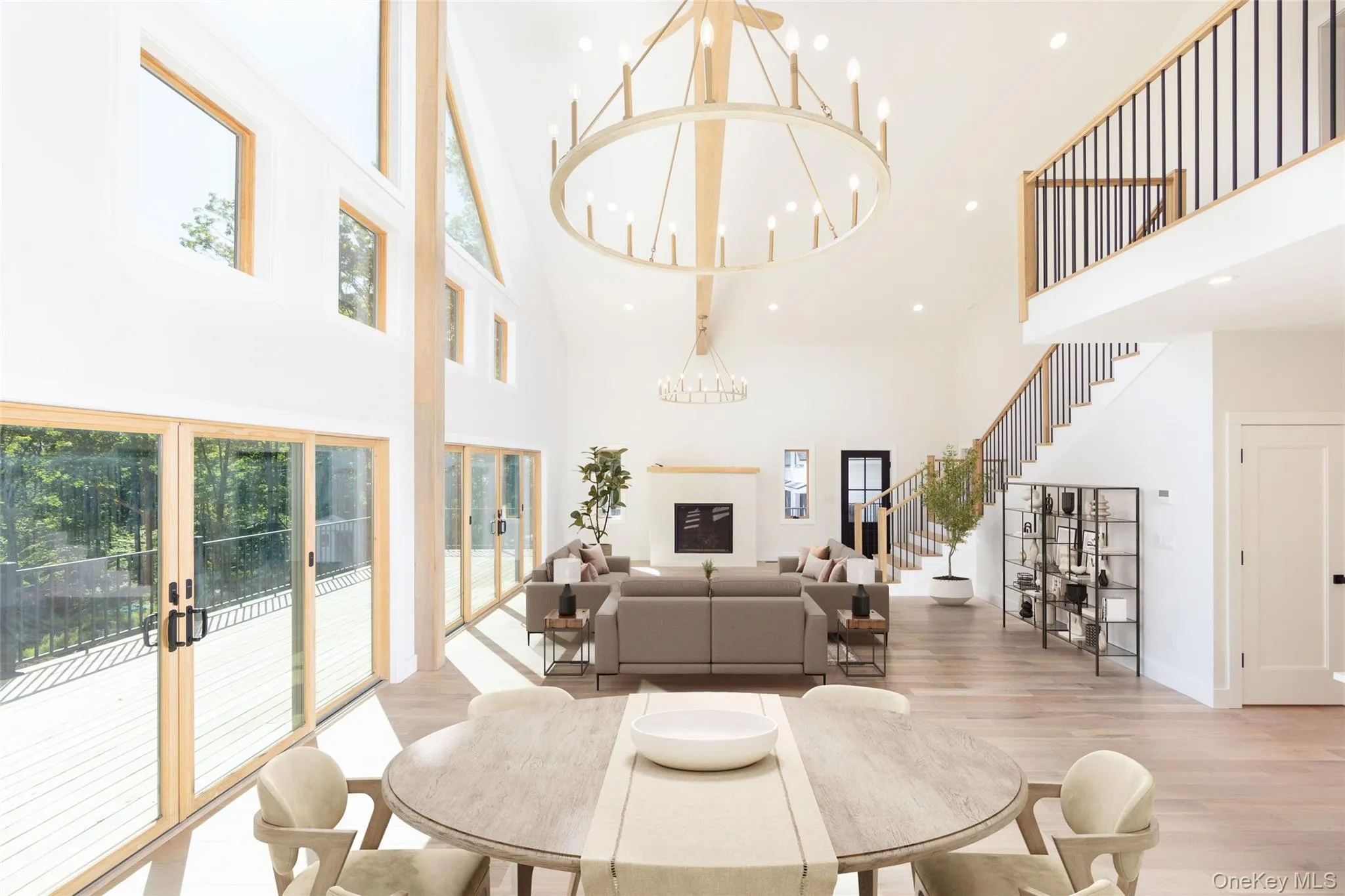 Vaulted ceiling living space featuring a fireplace, wood-finish flooring, a grand staircase Images have been virtually staged to illustrate the property's potential Vaulted ceiling living space featuring a fireplace, wood-finish flooring, a grand staircase Images have been virtually staged to illustrate the property's potential