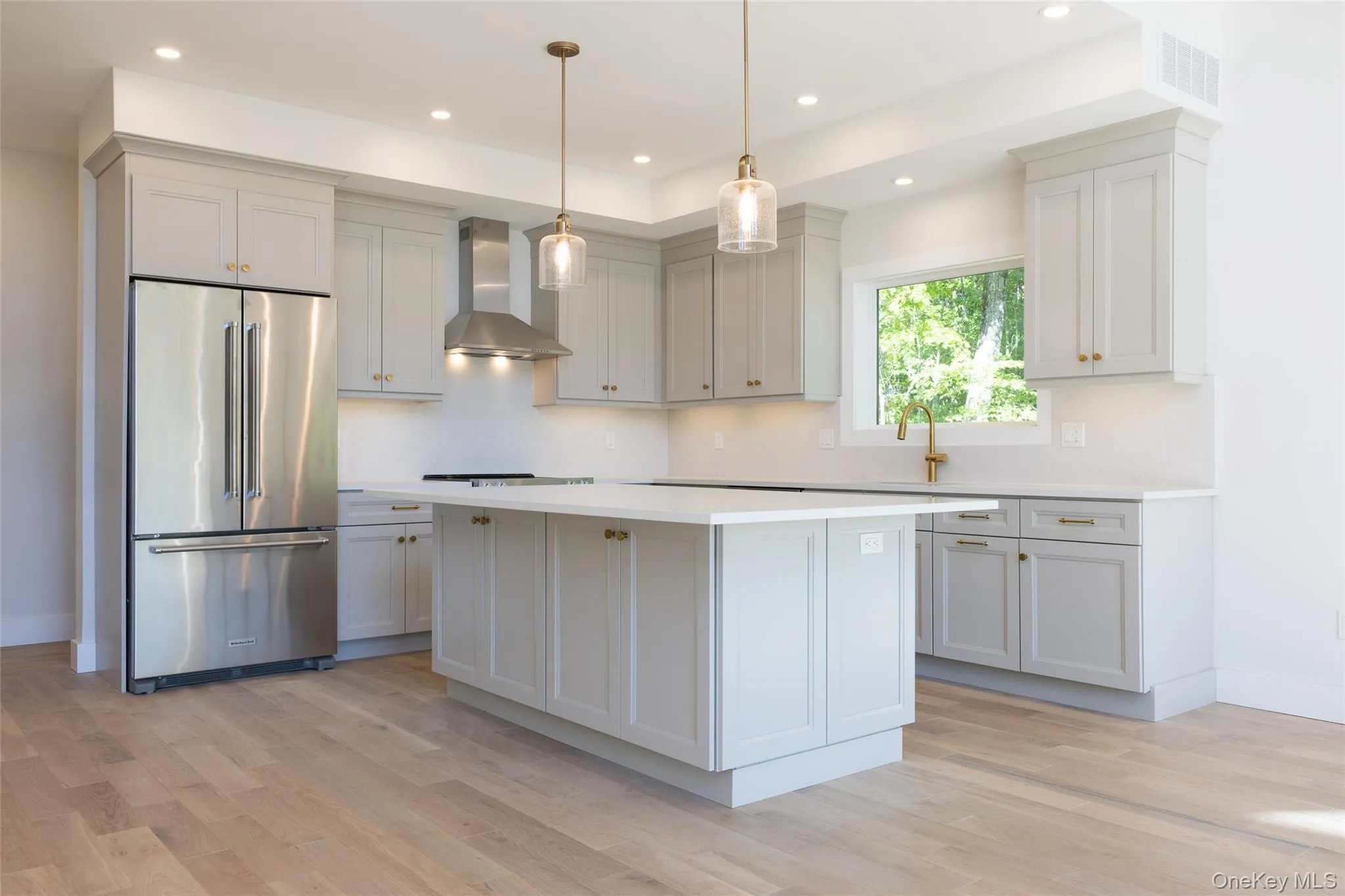Contemporary kitchen featuring light wood-finish flooring, light grey cabinetry, a central island, stainless steel appliances, and recessed lighting Contemporary kitchen featuring light wood-finish flooring, light grey cabinetry, a central island, stainless steel appliances, and recessed lighting