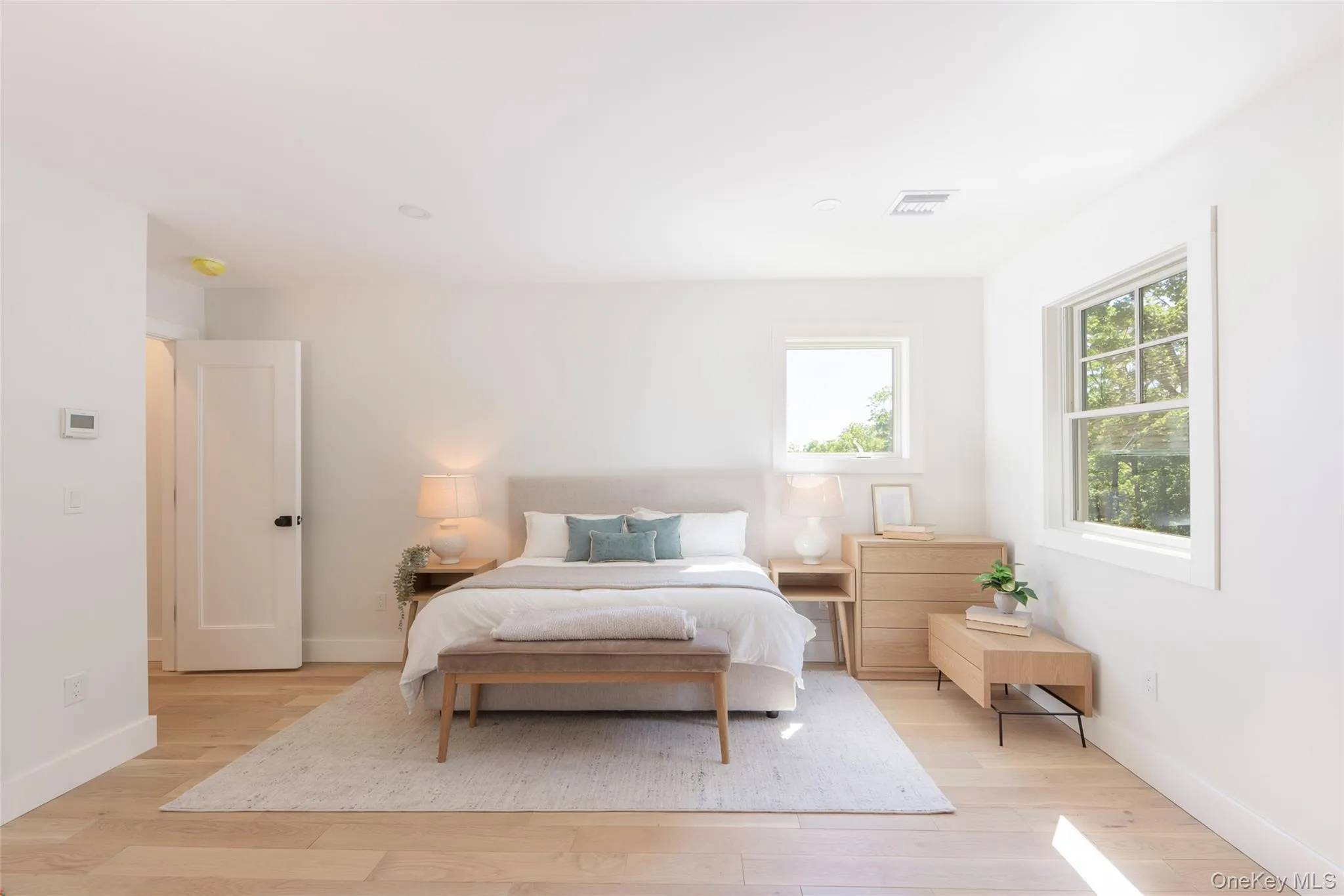 Bright bedroom featuring light wood-finish flooring, white walls, and multiple windowsImages have been virtually staged to illustrate the property's potential Bright bedroom featuring light wood-finish flooring, white walls, and multiple windowsImages have been virtually staged to illustrate the property's potential