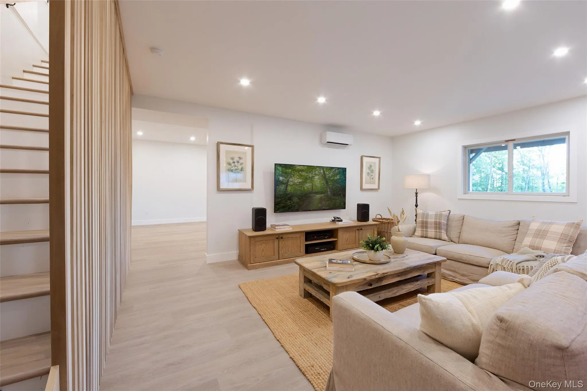 Living area featuring recessed lighting, light wood-finish flooring, a contemporary staircase with vertical wood slat railing, and a window with exterior sceneryImages have been virtually staged to illustrate the property's potential Living area featuring recessed lighting, light wood-finish flooring, a contemporary staircase with vertical wood slat railing, and a window with exterior sceneryImages have been virtually staged to illustrate the property's potential