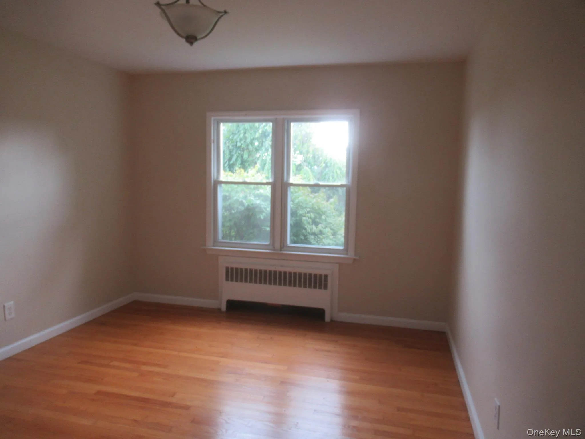 Empty room featuring radiator heating unit and light wood-type flooring Empty room featuring radiator heating unit and light wood-type flooring