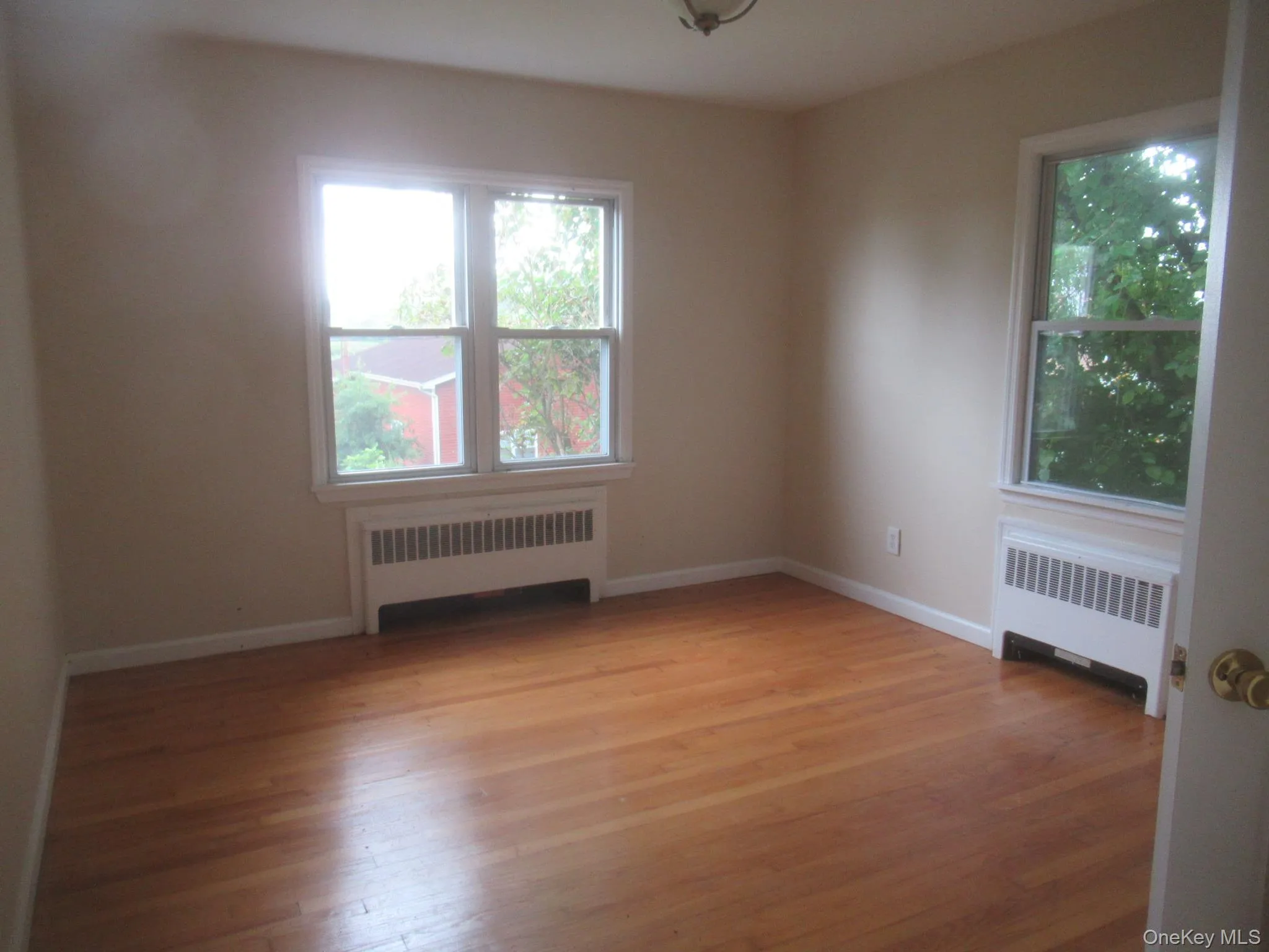 Empty room featuring radiator and light wood finished floors Empty room featuring radiator and light wood finished floors