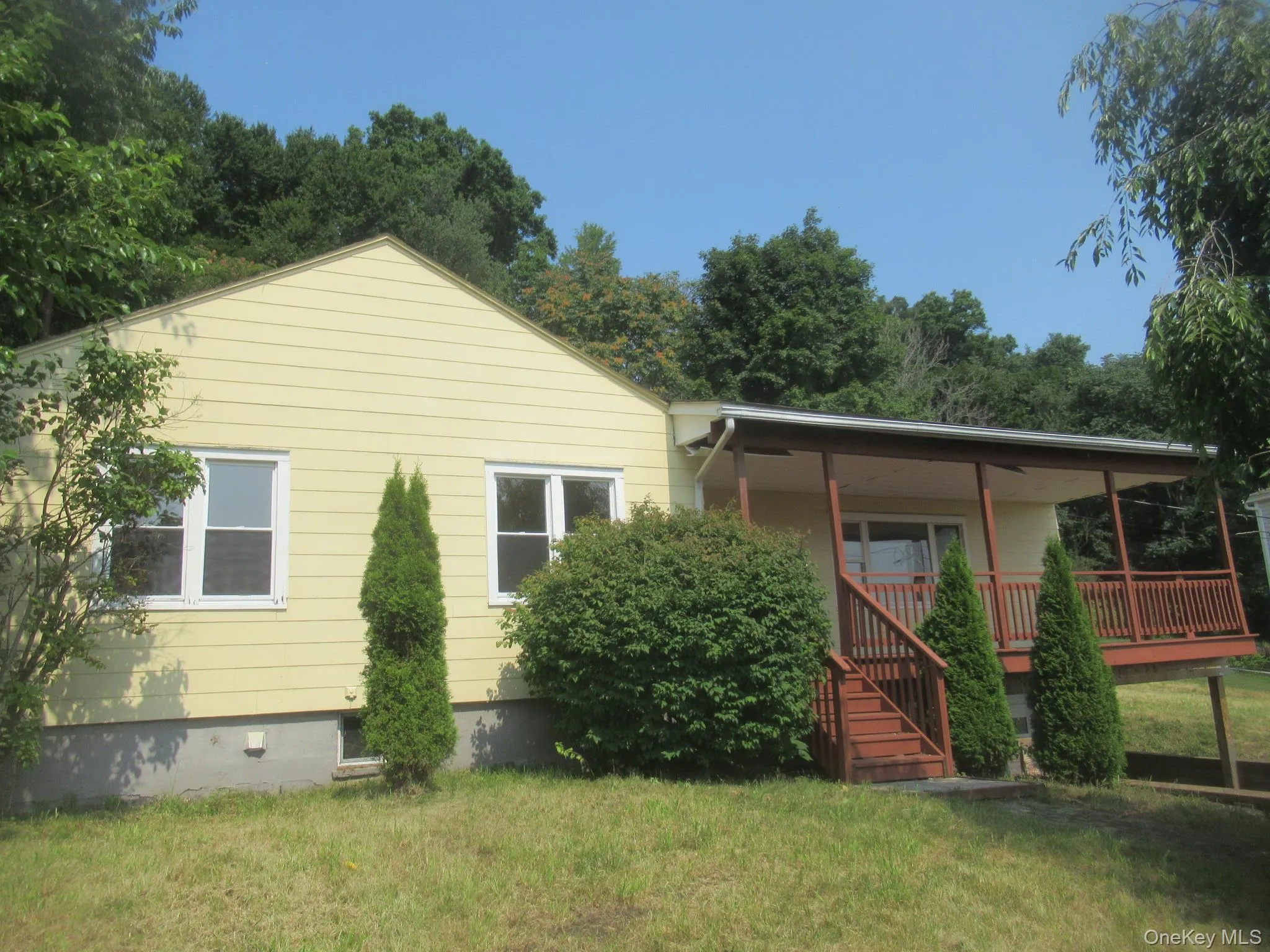 View of front of property with covered porch, stairway, and a front lawn View of front of property with covered porch, stairway, and a front lawn