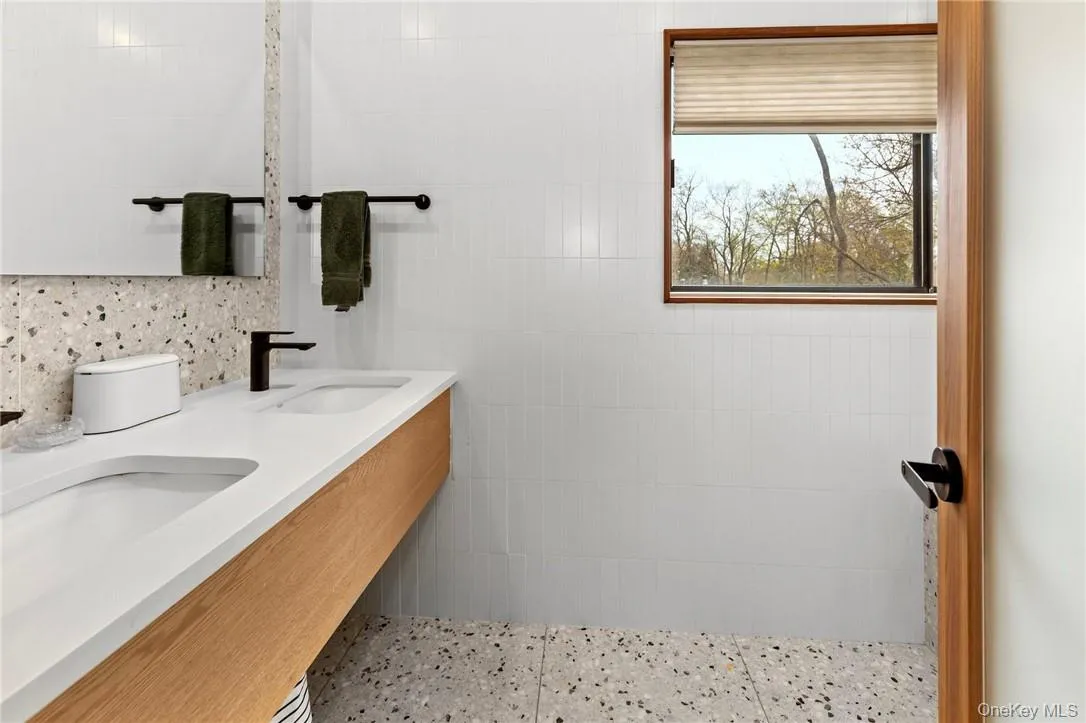 Elegant primary suite bathroom featuring a double vanity, large mirror, and ample natural light, providing a serene and functional space. Elegant primary suite bathroom featuring a double vanity, large mirror, and ample natural light, providing a serene and functional space.