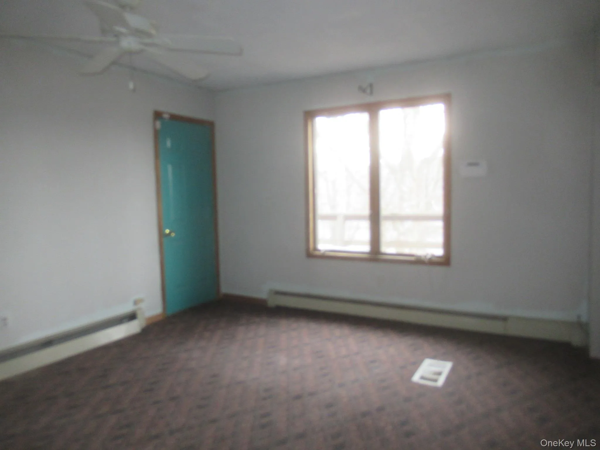 Spare room featuring a baseboard radiator, dark colored carpet, and a ceiling fan Spare room featuring a baseboard radiator, dark colored carpet, and a ceiling fan