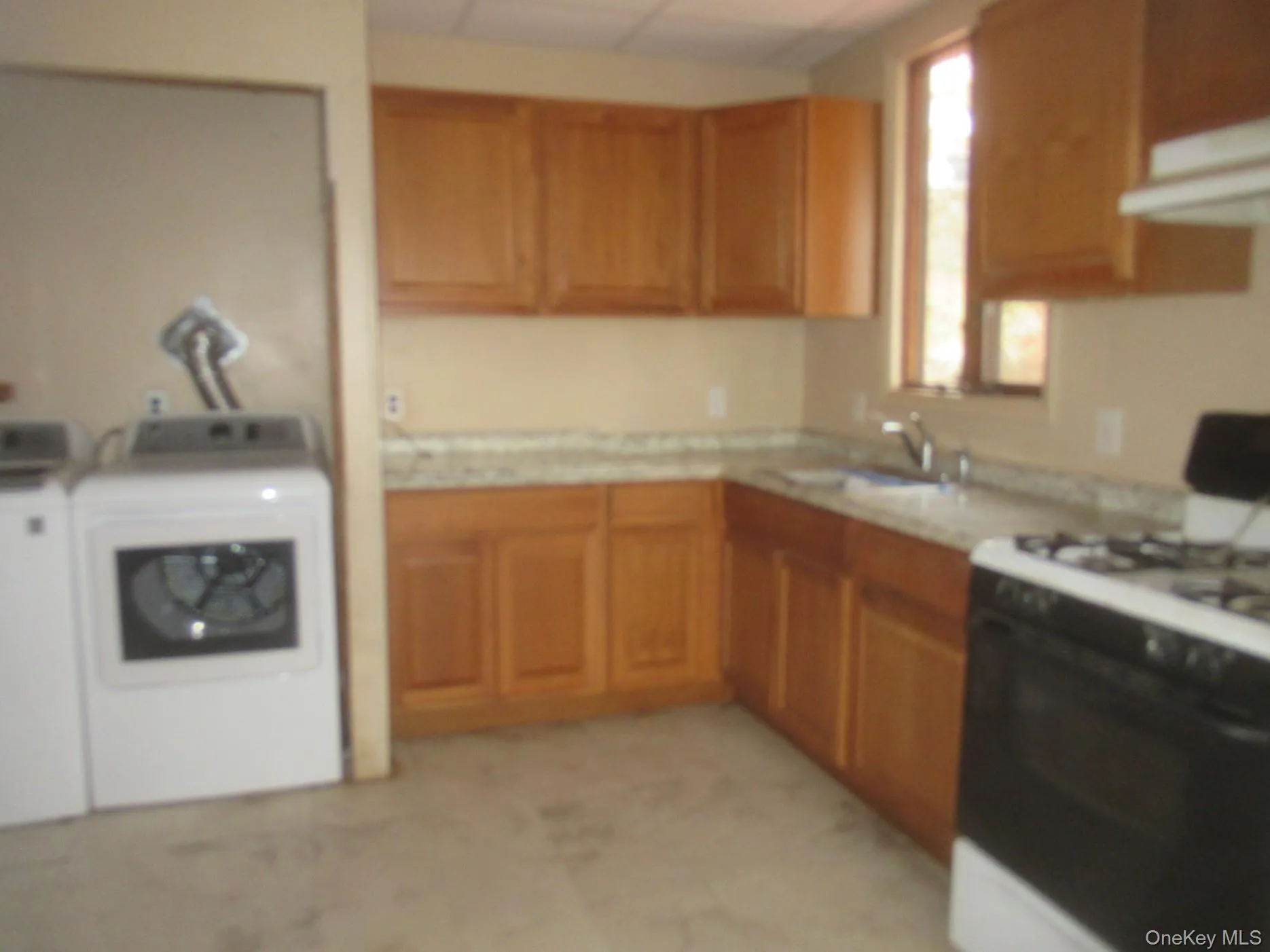 Kitchen featuring gas range oven, light countertops, and brown cabinets Kitchen featuring gas range oven, light countertops, and brown cabinets