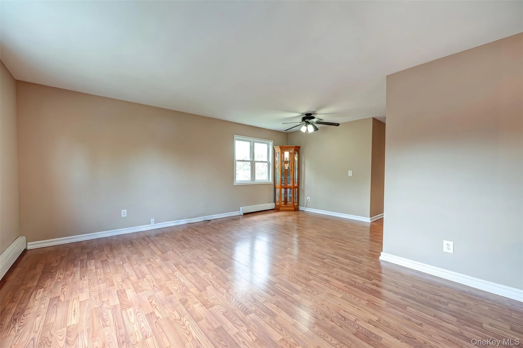 Spacious room featuring wood-finish flooring, neutral-toned walls, and white trim Spacious room featuring wood-finish flooring, neutral-toned walls, and white trim