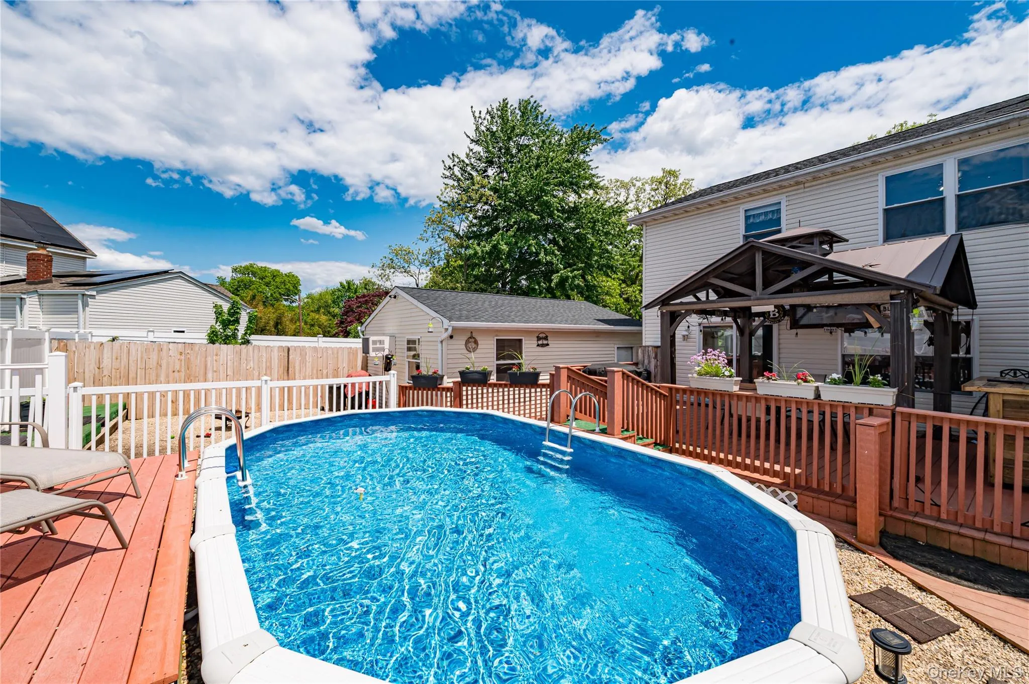 Outdoor pool area featuring an above-ground pool, expansive wood decking, and a covered pergola Outdoor pool area featuring an above-ground pool, expansive wood decking, and a covered pergola
