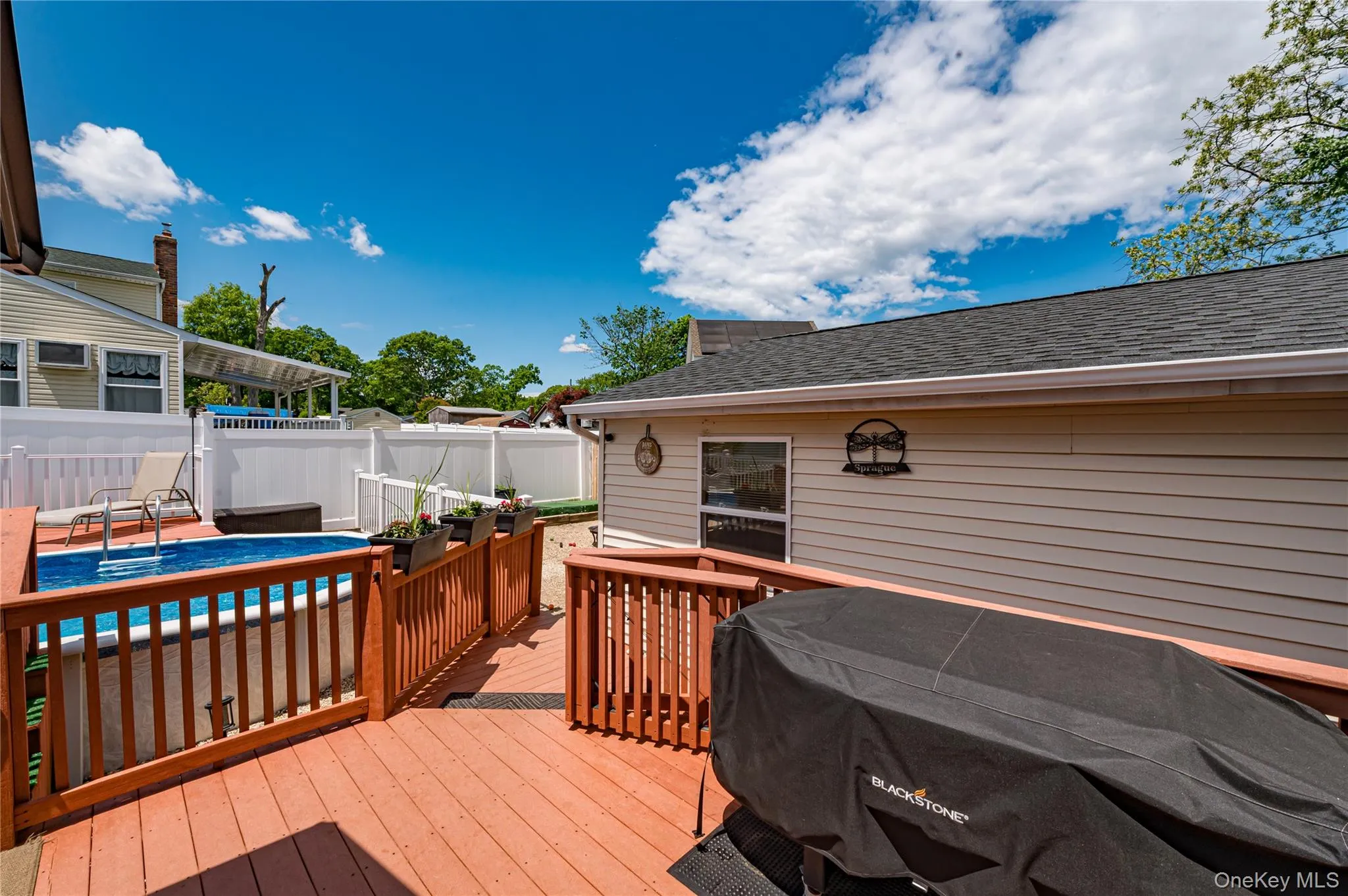 Expansive wood deck with a built-in above-ground pool, surrounded by white privacy fencing Expansive wood deck with a built-in above-ground pool, surrounded by white privacy fencing