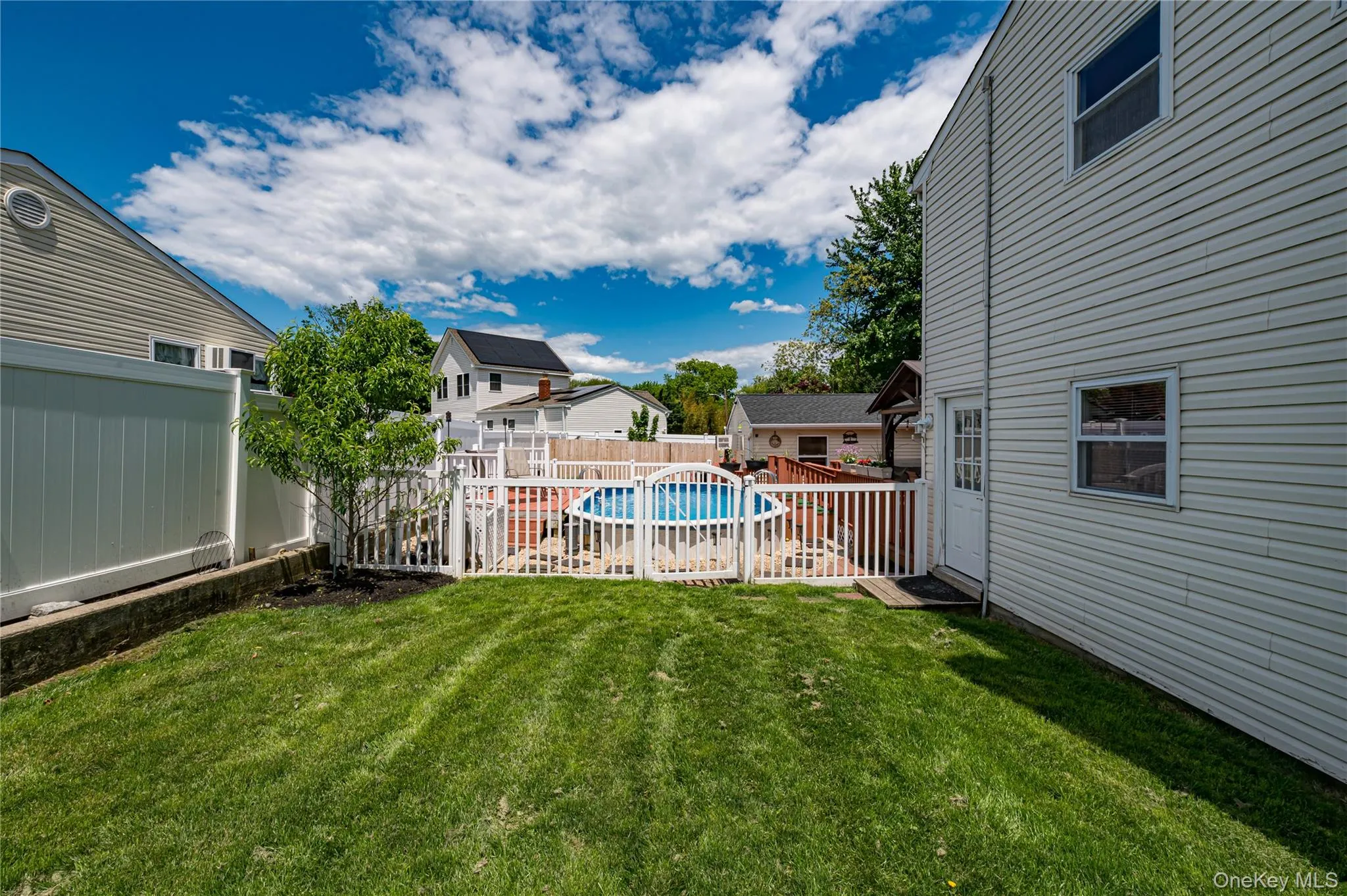 Expansive green lawn with a white picket fence enclosing an above-ground pool Expansive green lawn with a white picket fence enclosing an above-ground pool