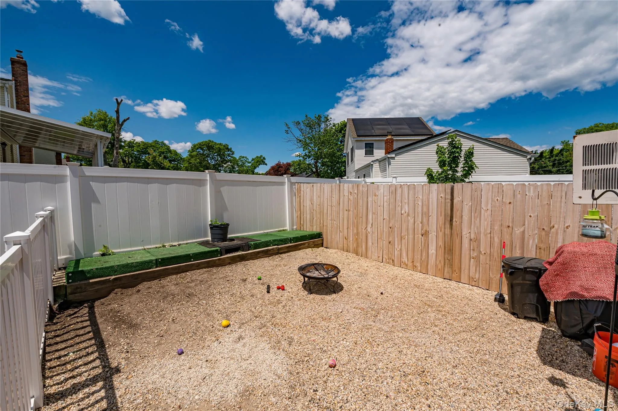 Private backyard featuring a gravel surface, white vinyl fencing, and natural wood privacy fencing Private backyard featuring a gravel surface, white vinyl fencing, and natural wood privacy fencing