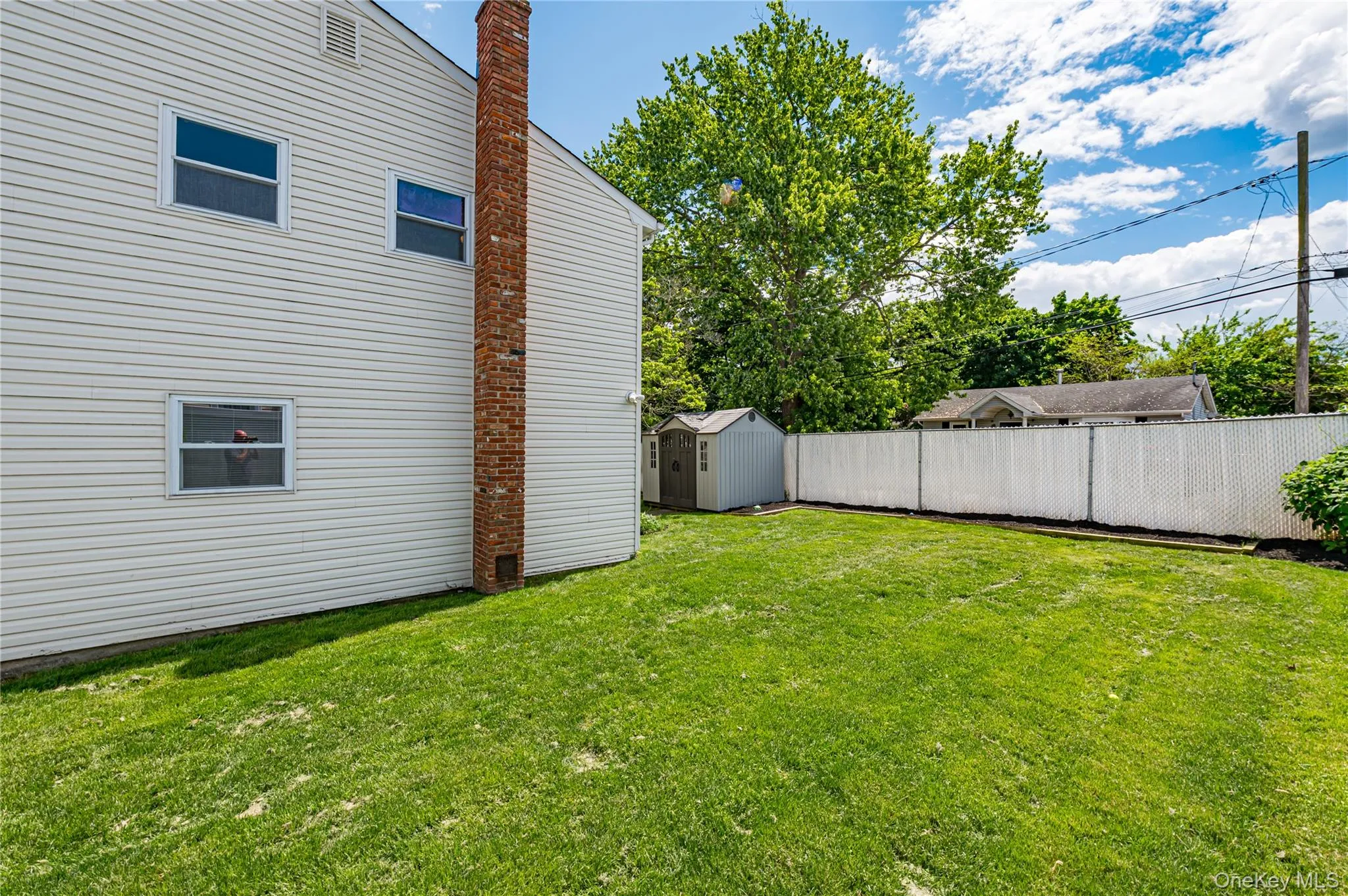 Expansive green lawn with a white vinyl fence and a detached storage shed Expansive green lawn with a white vinyl fence and a detached storage shed