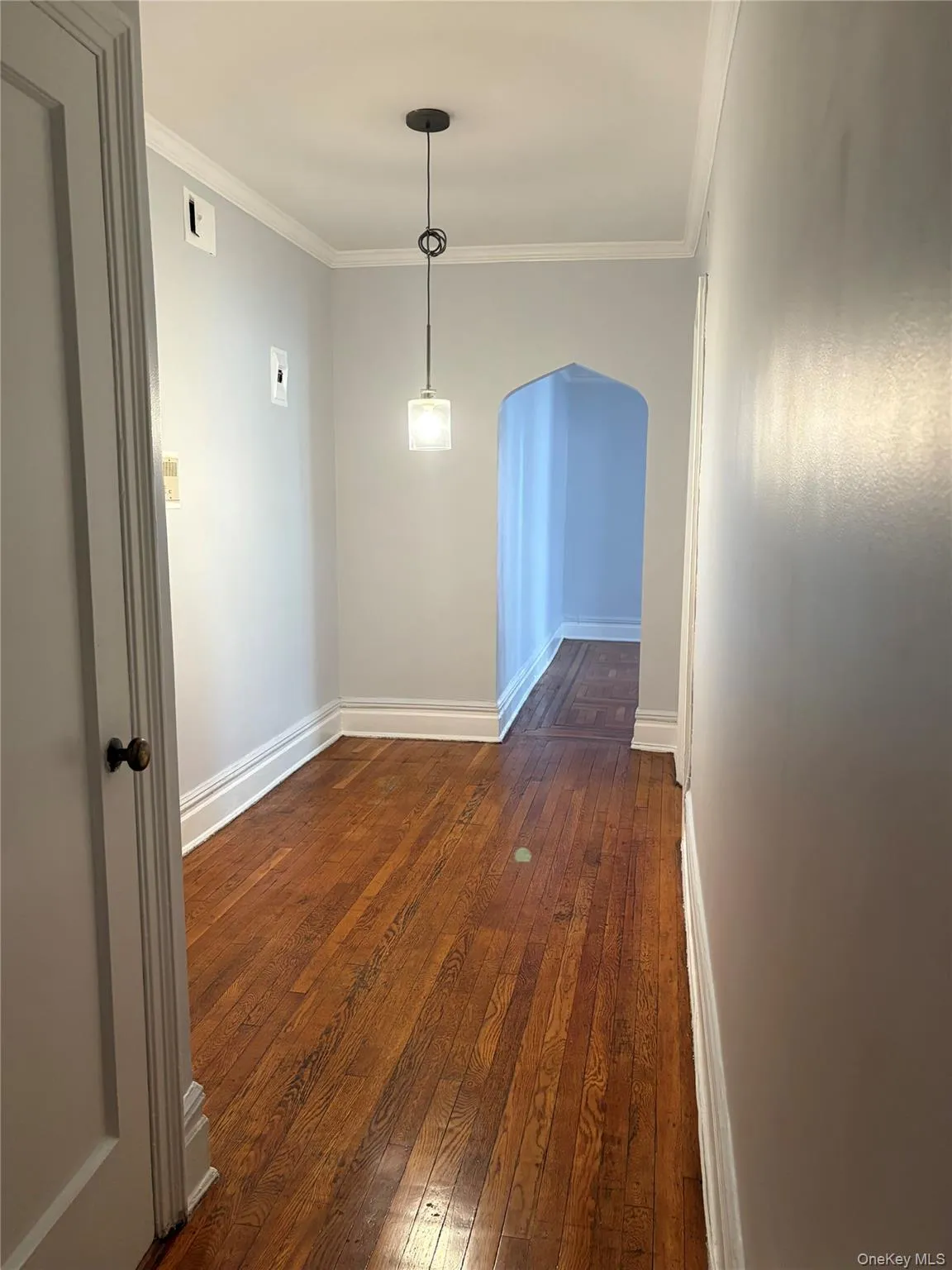 Spare room with dark wood-style flooring, crown molding, and arched walkways Spare room with dark wood-style flooring, crown molding, and arched walkways