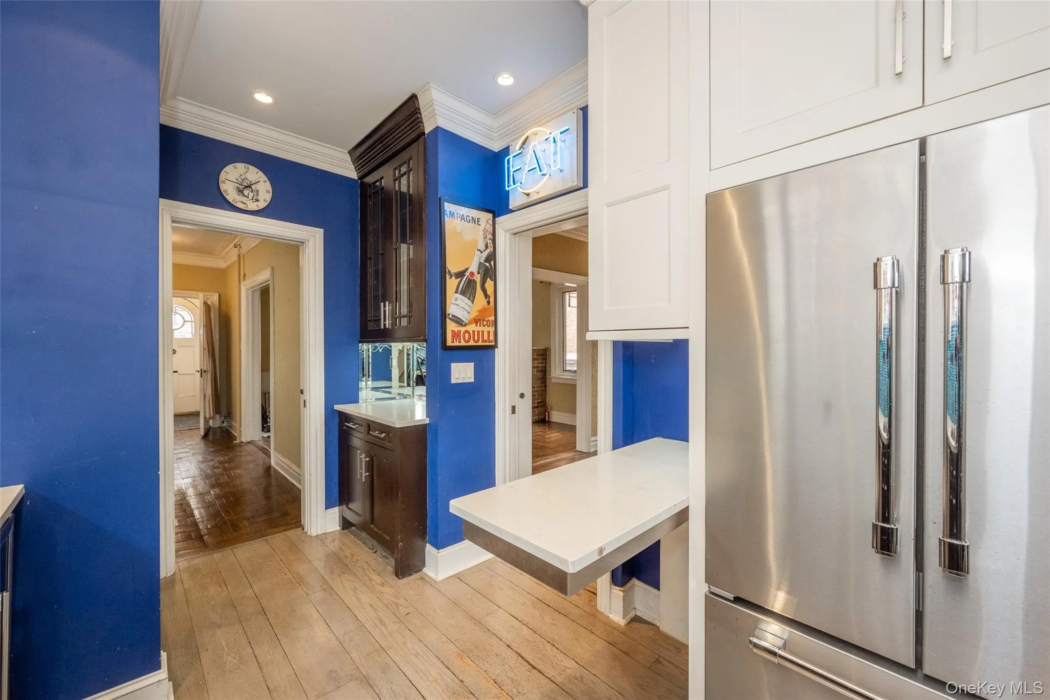 Kitchen area featuring wood-finish flooring, white cabinetry, and a stainless steel refrigerator Kitchen area featuring wood-finish flooring, white cabinetry, and a stainless steel refrigerator