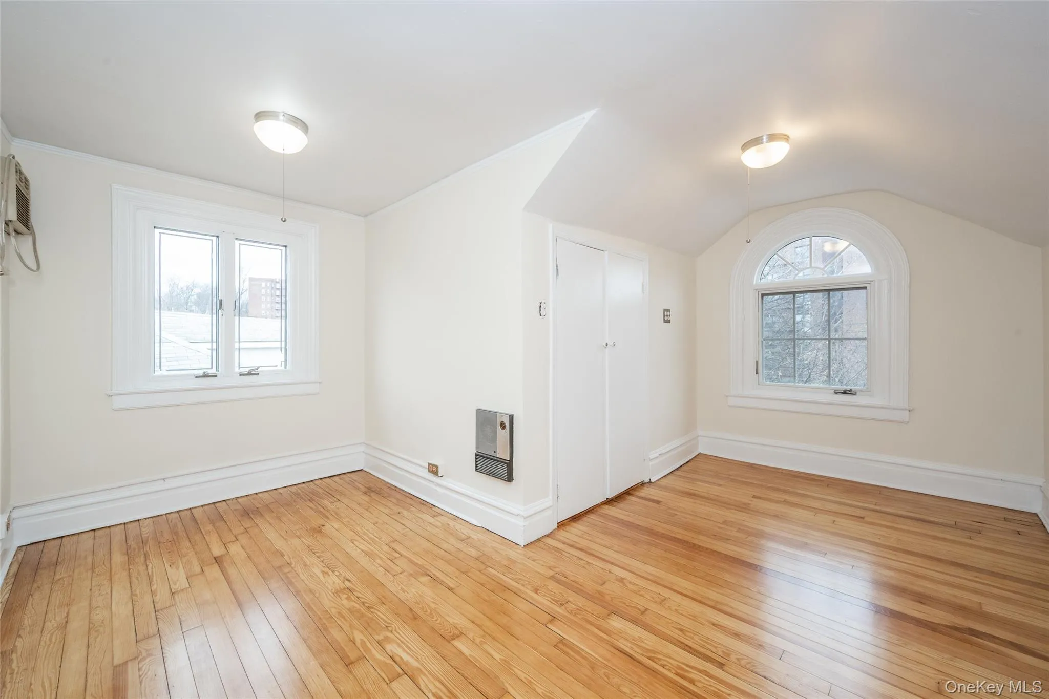 Bedroom #4 with wood-finish flooring, featuring a double casement window and an arched window Bedroom #4 with wood-finish flooring, featuring a double casement window and an arched window