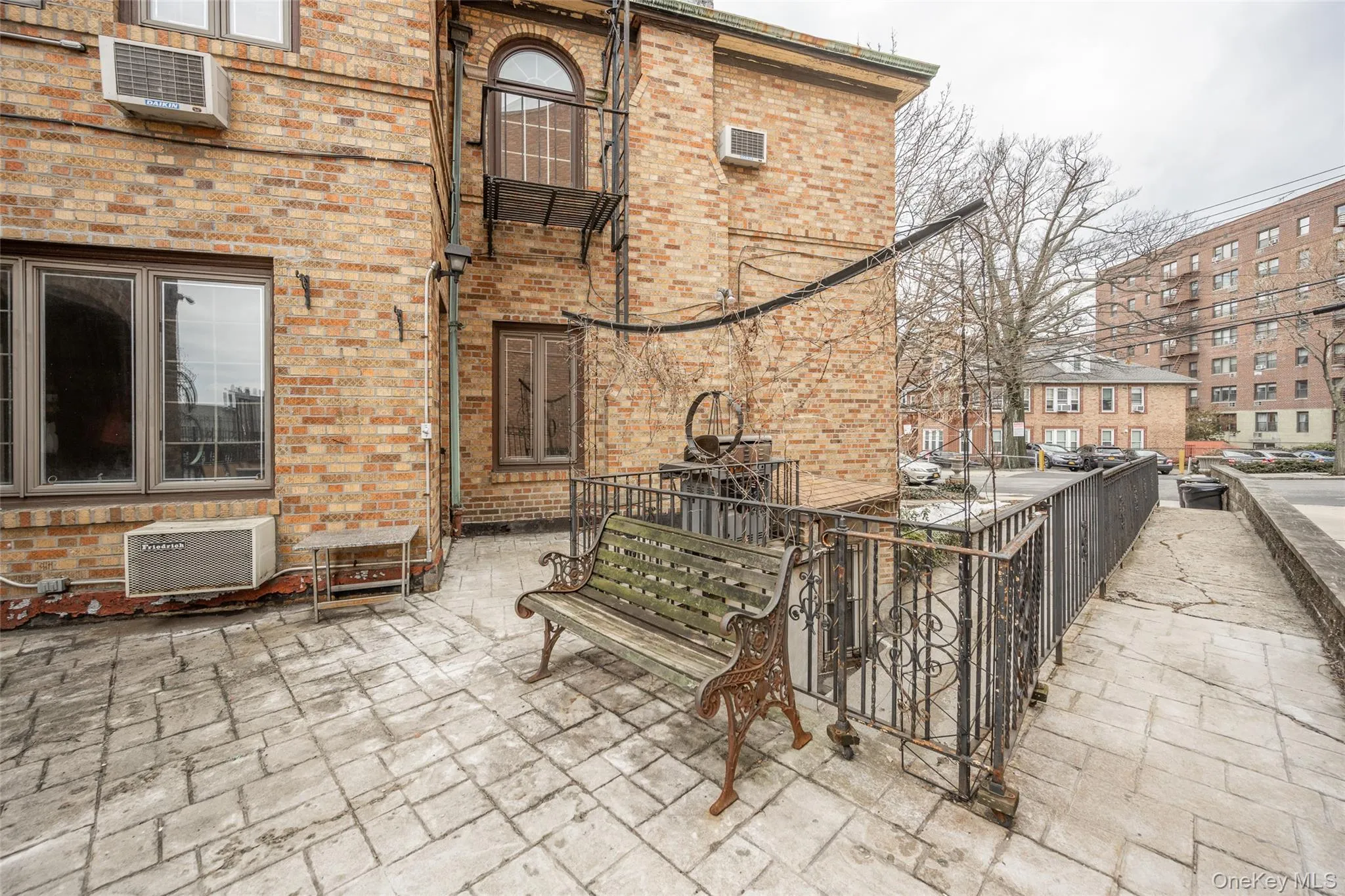 Brick exterior with multiple windows, featuring a patterned concrete patio Brick exterior with multiple windows, featuring a patterned concrete patio
